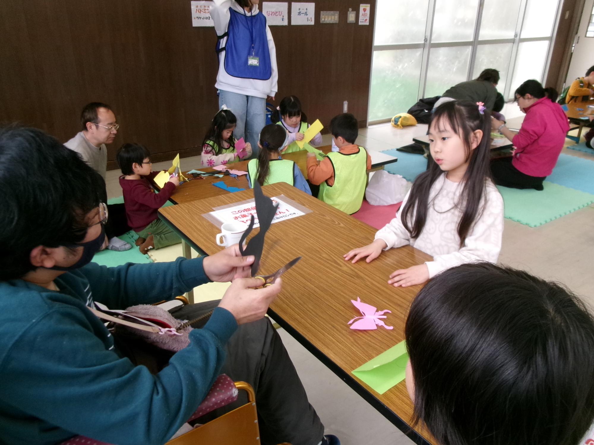 猫の切り絵を作った児童が、大薗さんに顔を切ってもらっている様子の写真