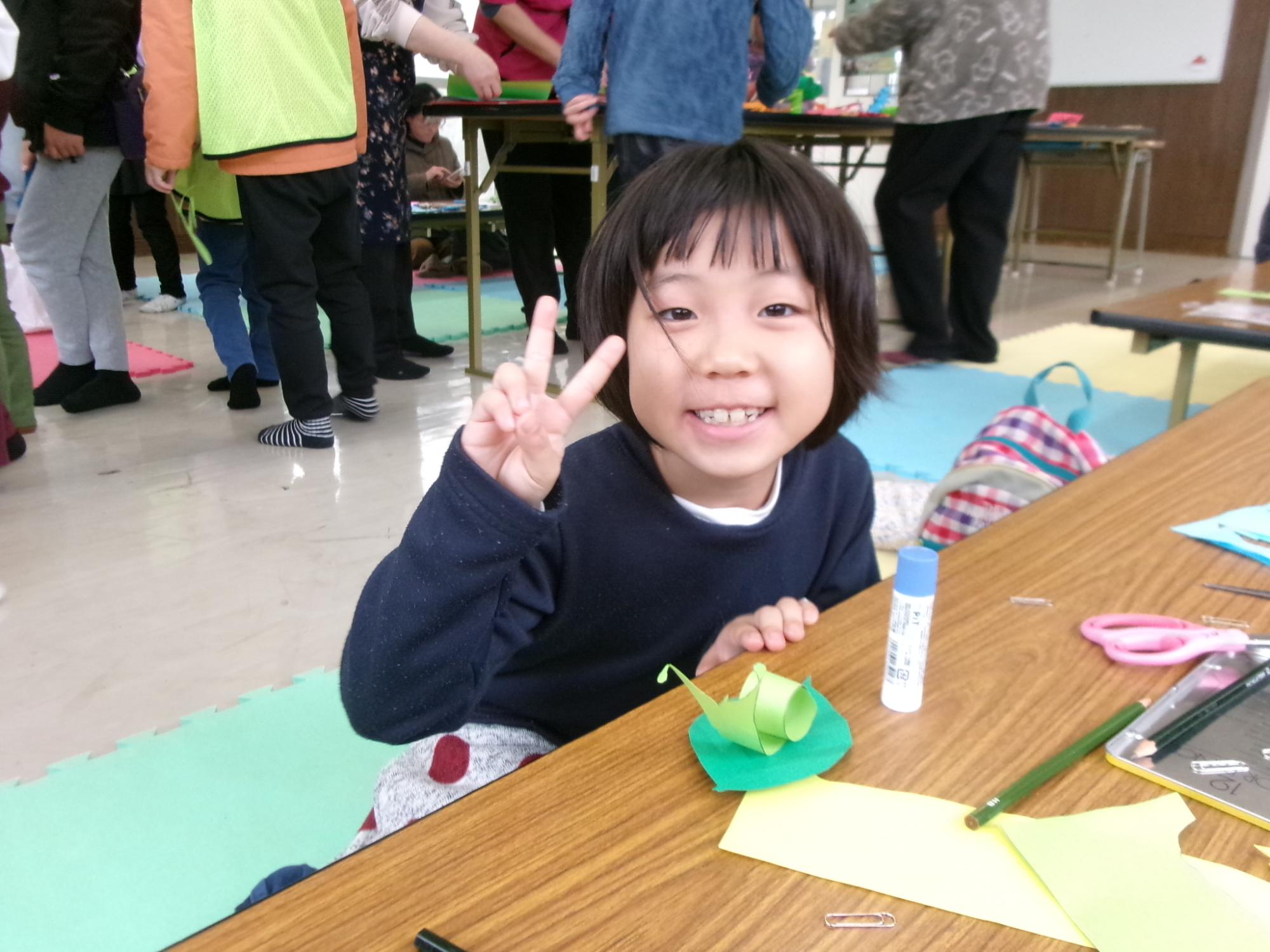 完成したかたつむりの切り絵と一緒に写っている児童の写真