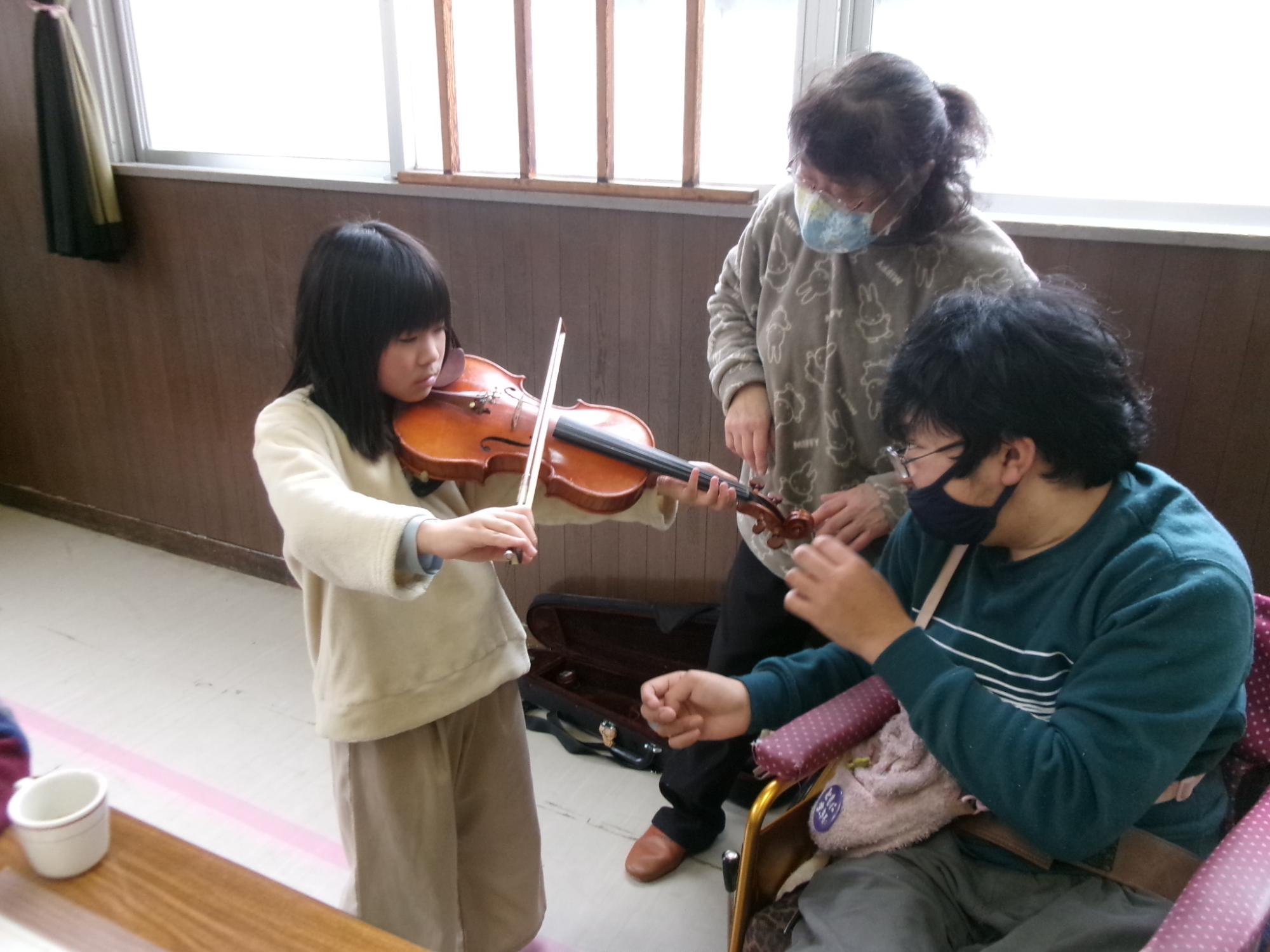 ヴァイオリンの体験をさせてもらっている児童の写真