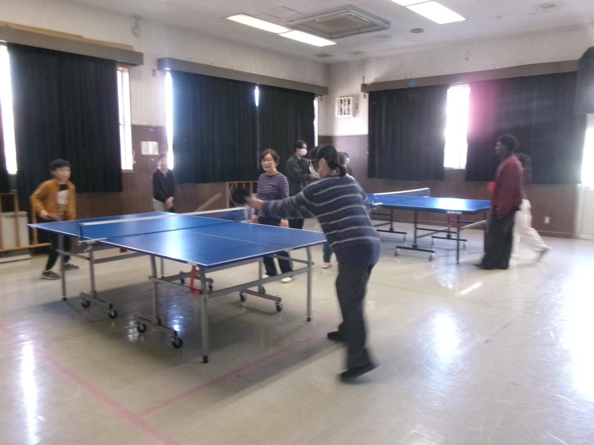 2台の卓球台で卓球を楽しんでいる参加者の写真