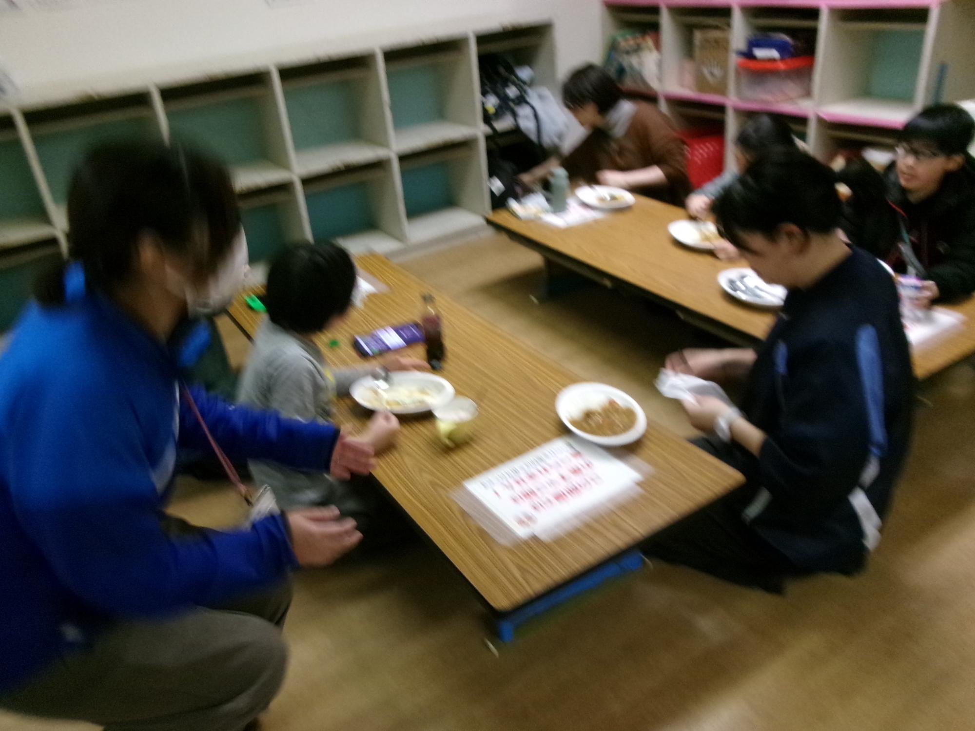 保護者と小学生が一緒にカレーを食べている様子の写真