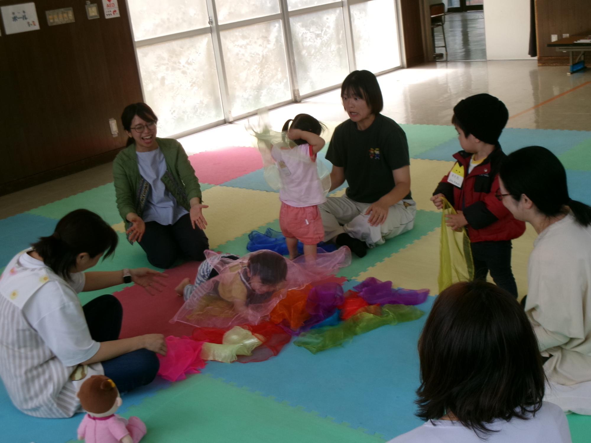 乳幼児親子がカラフルなガーゼで遊んでいる様子