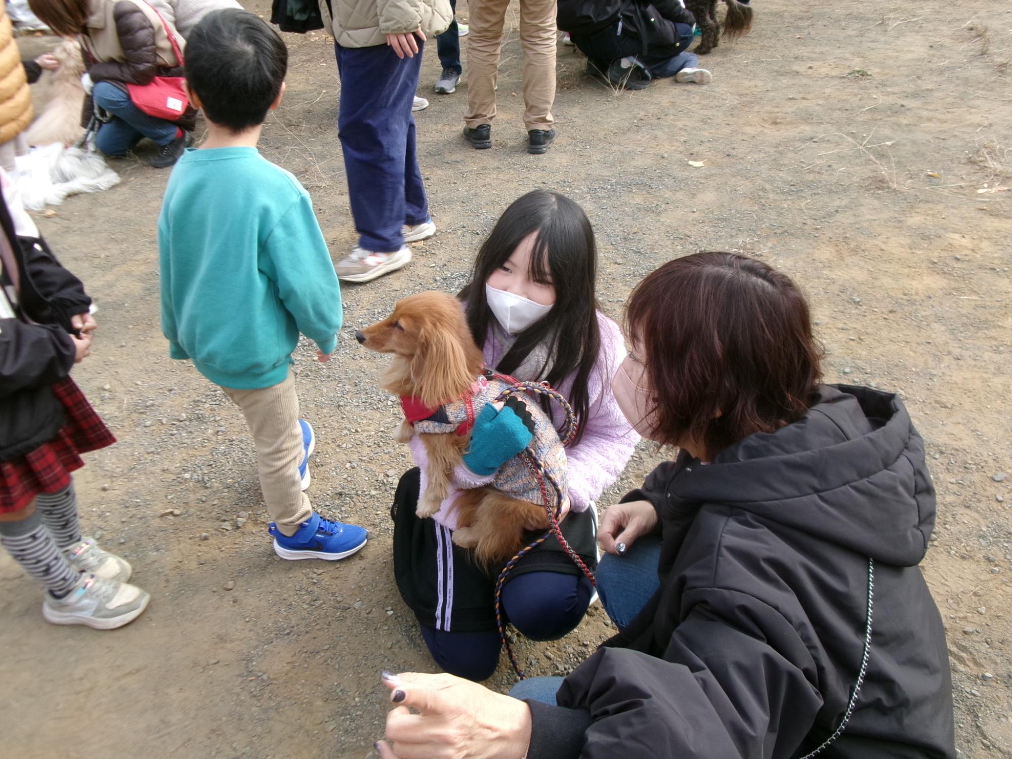 犬を抱っこさせてもらっている子どもの写真