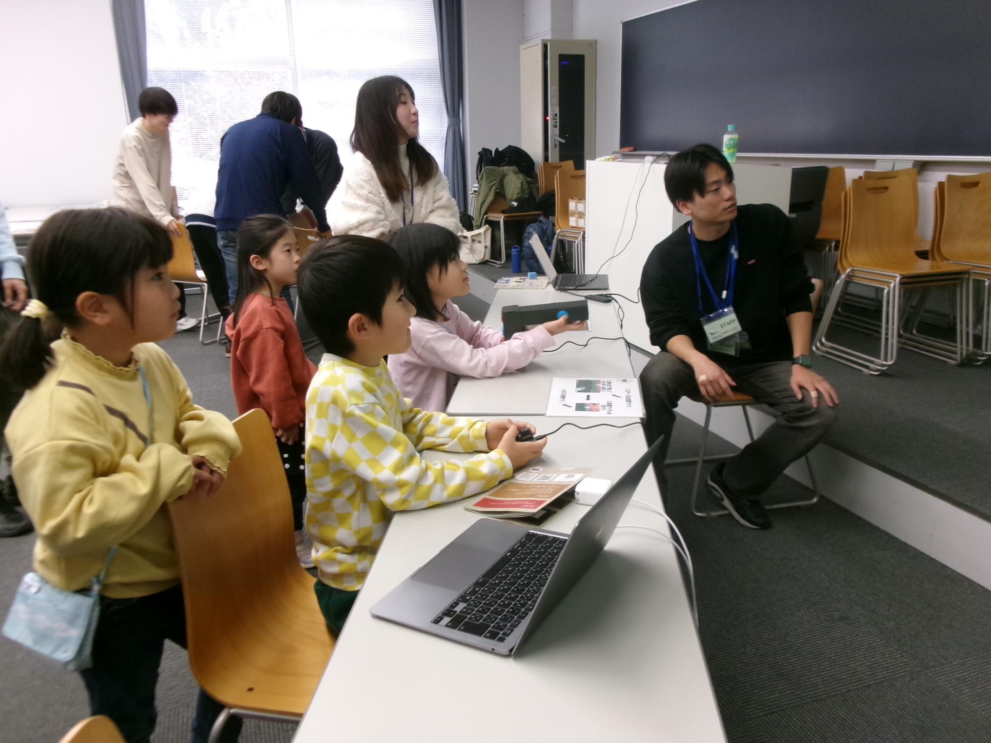 学生手作りのシューティングゲームを楽しんでいる子どもたちの写真