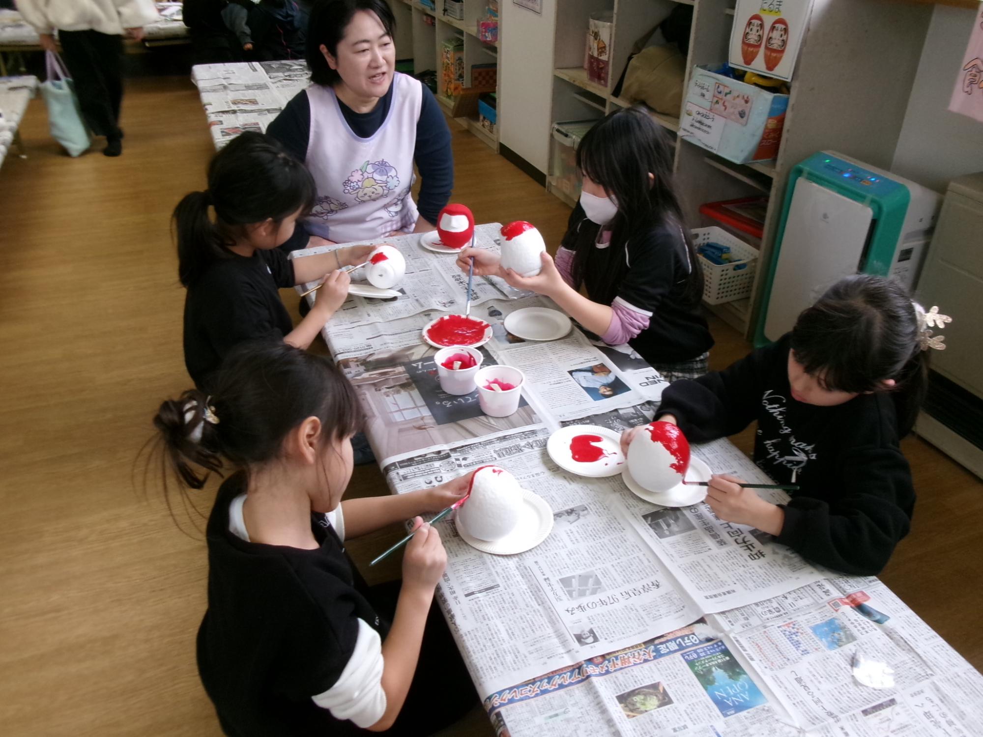 だるまを赤に塗っている子どもたちの様子の写真