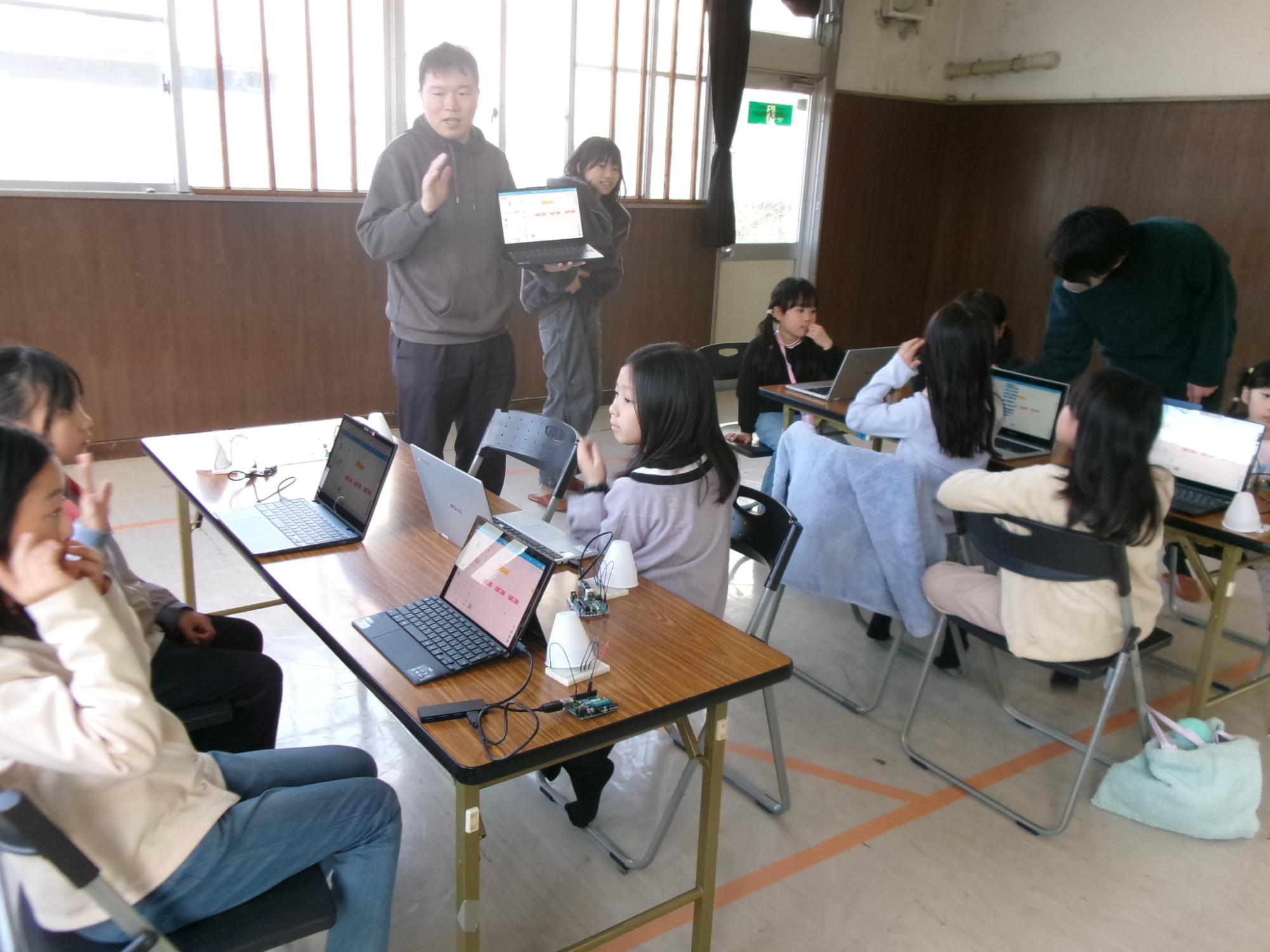 講師から光り方が変わるランタンのプログラミングについて説明を受けている参加者の写真