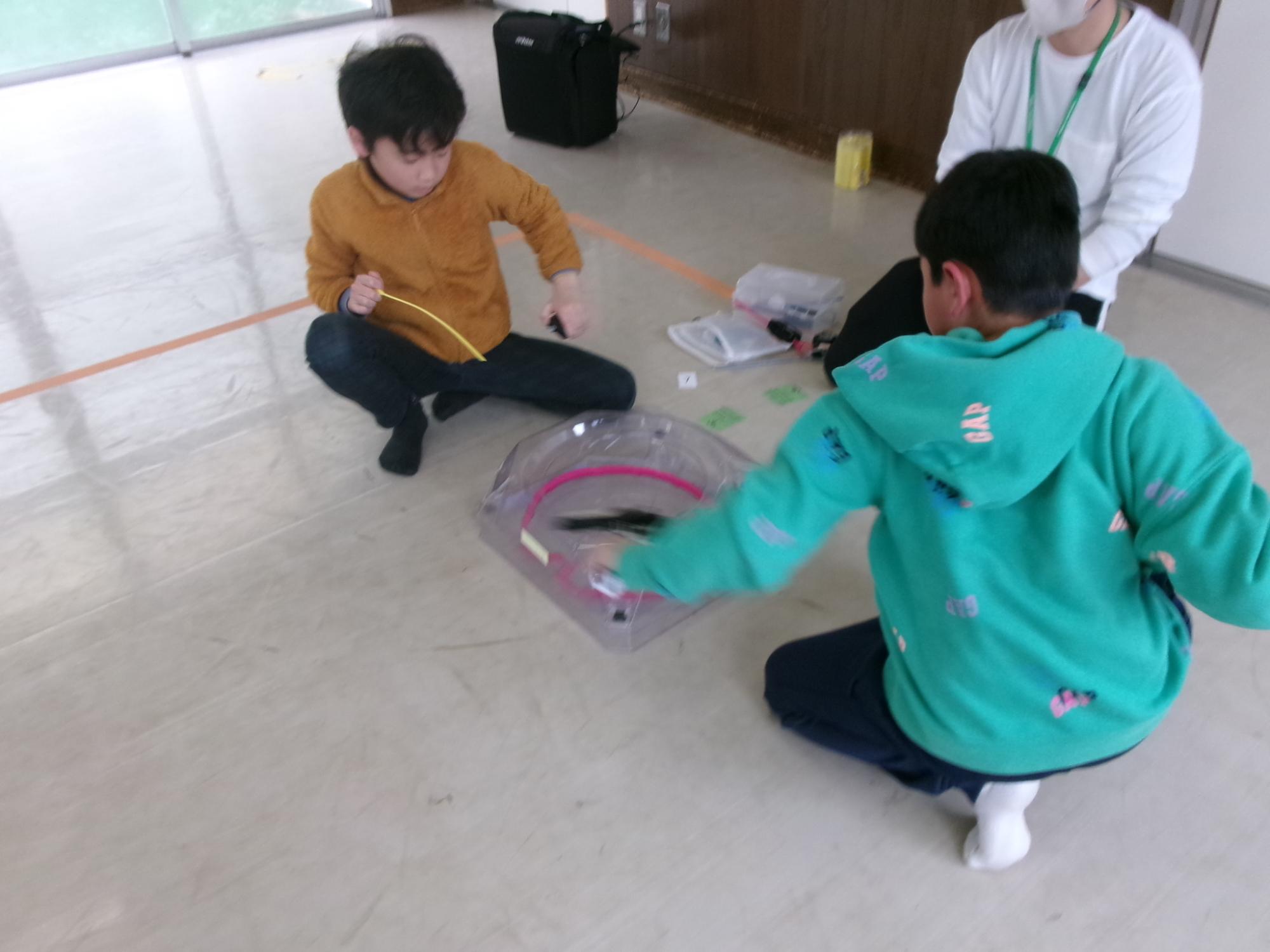 児童2名がベイブレード大会の決勝戦をしている様子の写真