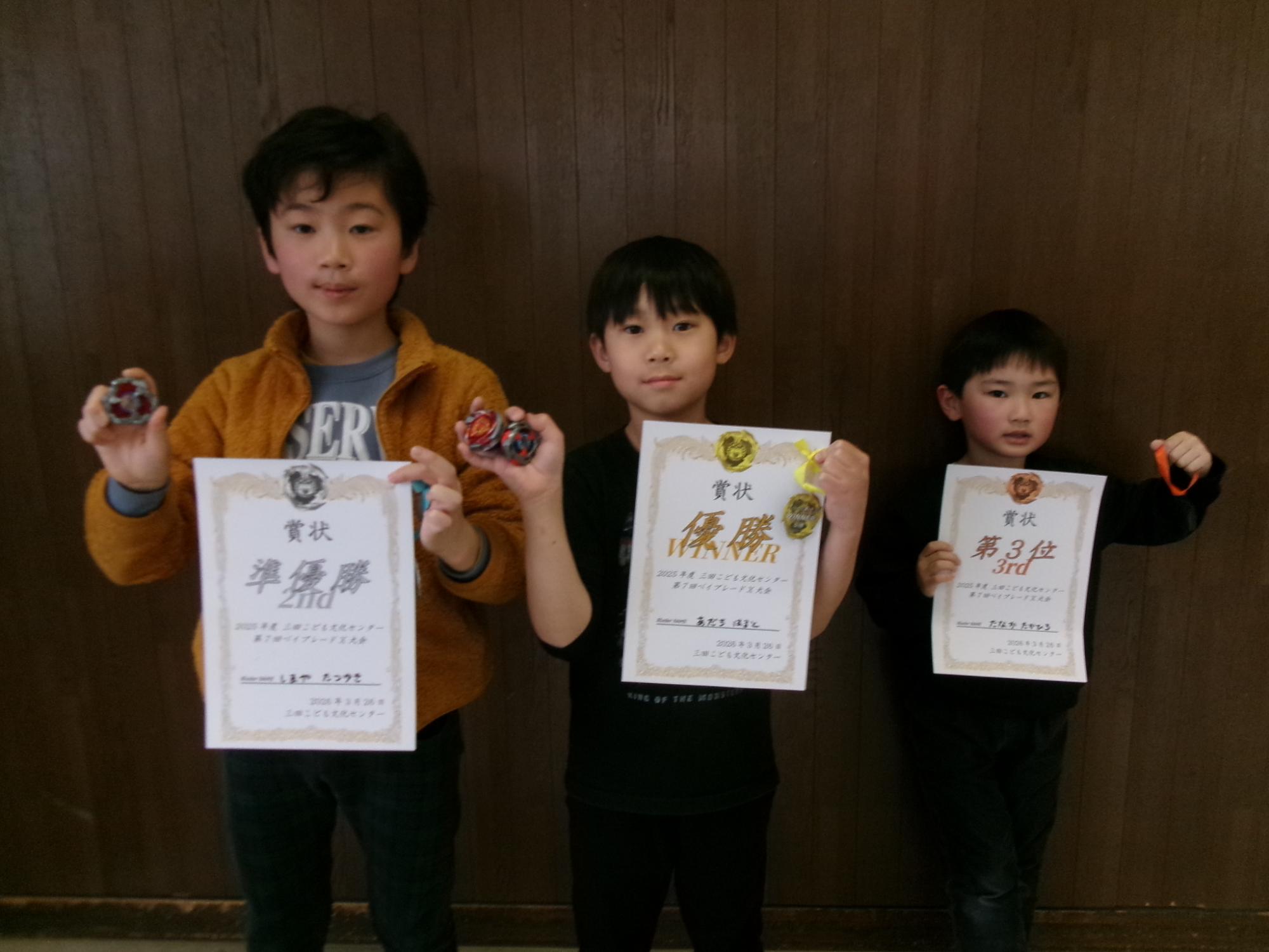 児童3名がベイブレード大会で表彰されている様子の写真