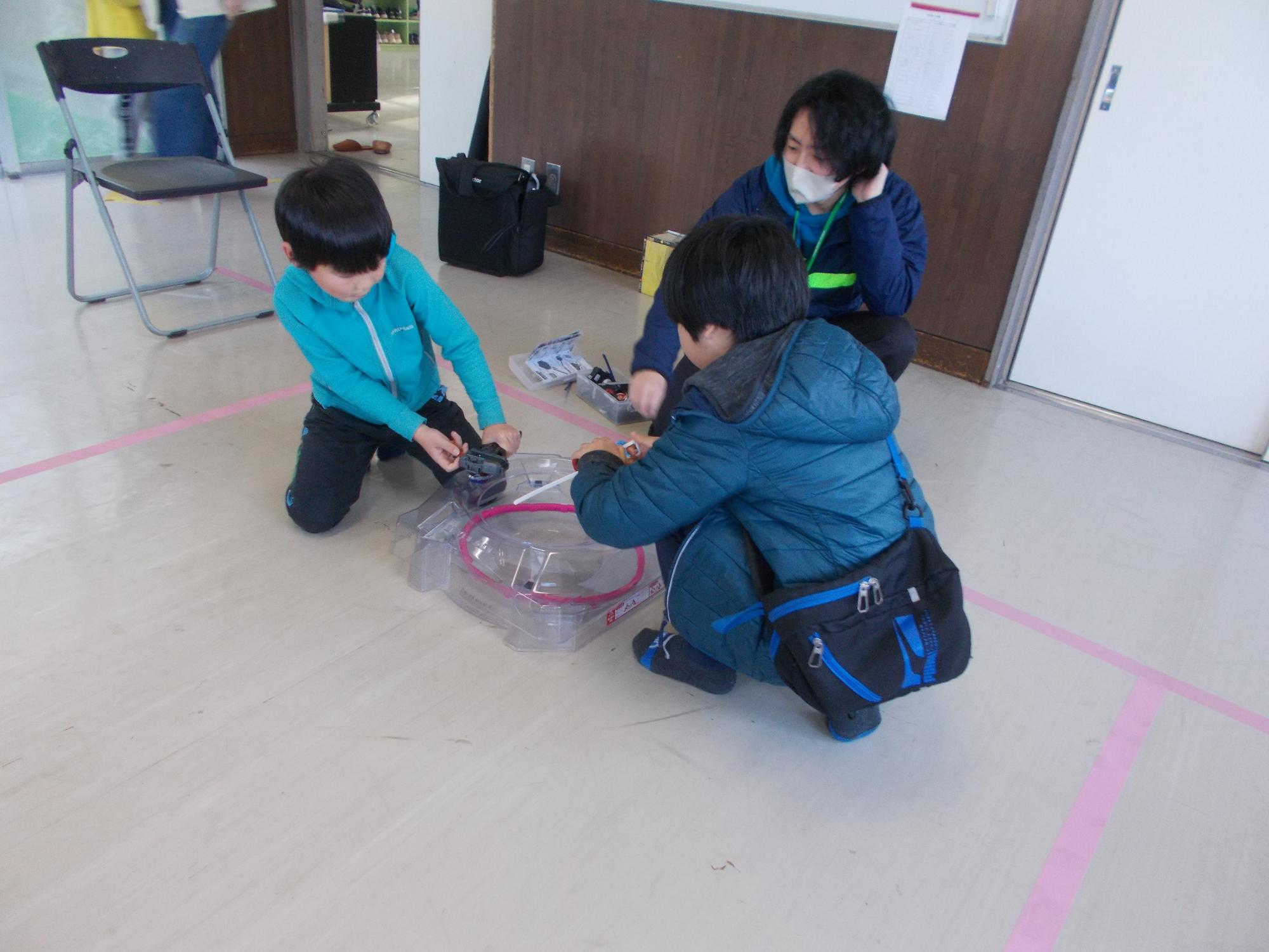 ベイブレードの対戦をしている子どもたちの写真