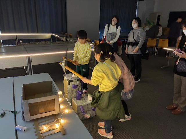 物語の一環としてつるはしで鉱石を取る体験をしている子どもたちの写真