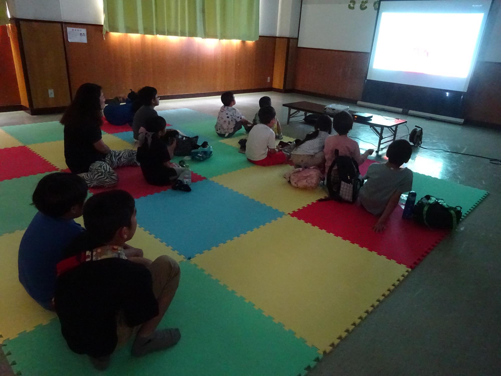 集会室の大型スクリーンで映画を見ている様子