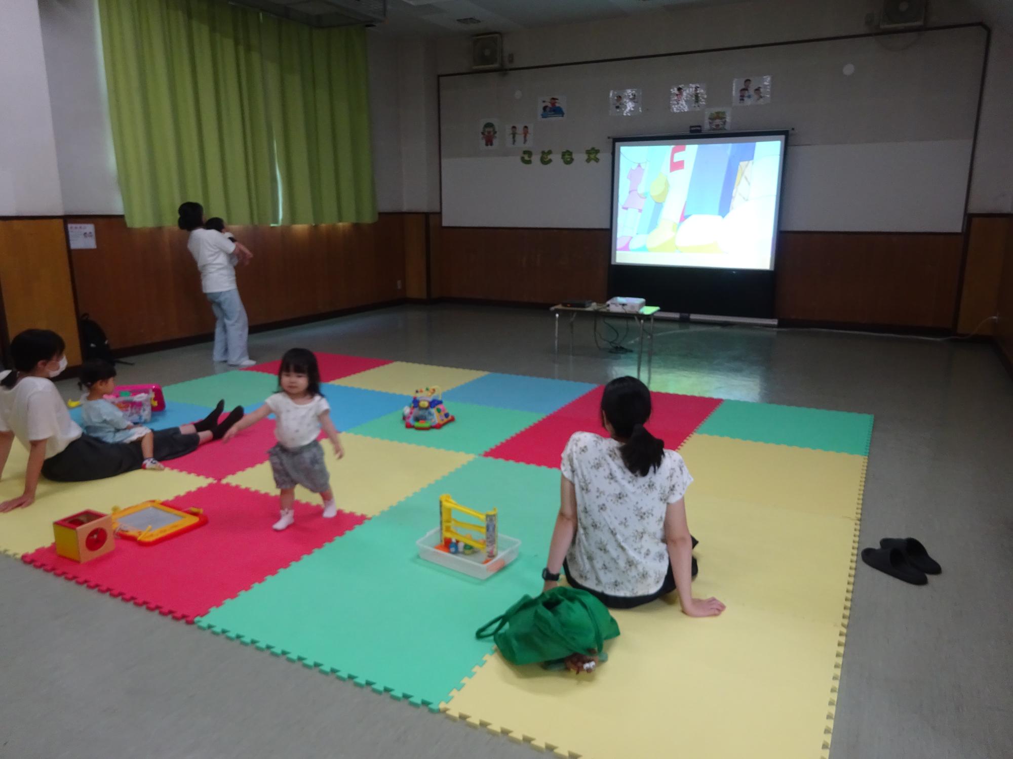 映画を見ている幼児親子の写真