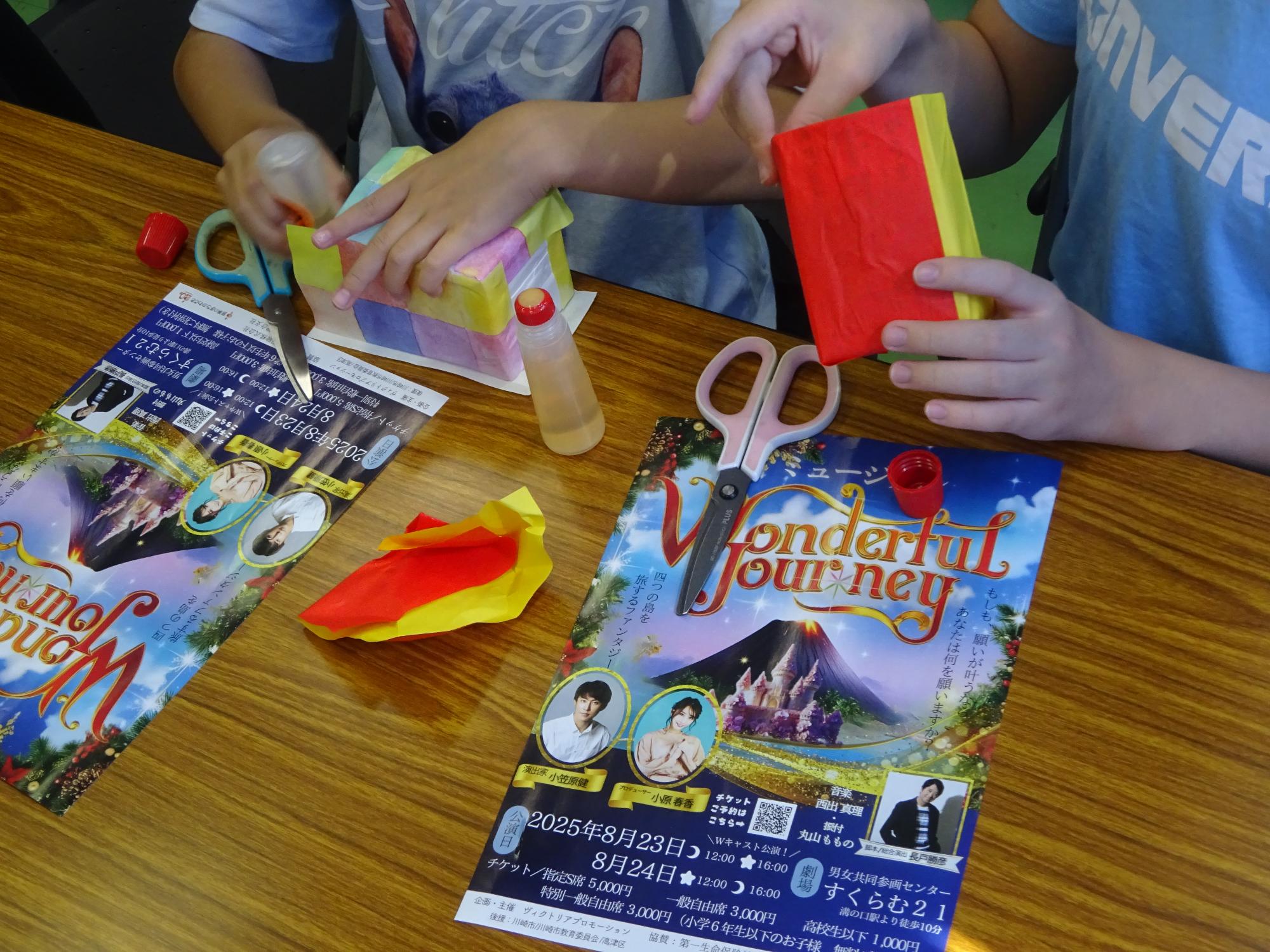 牛乳パックの周りに折り紙を貼っている子どもの写真