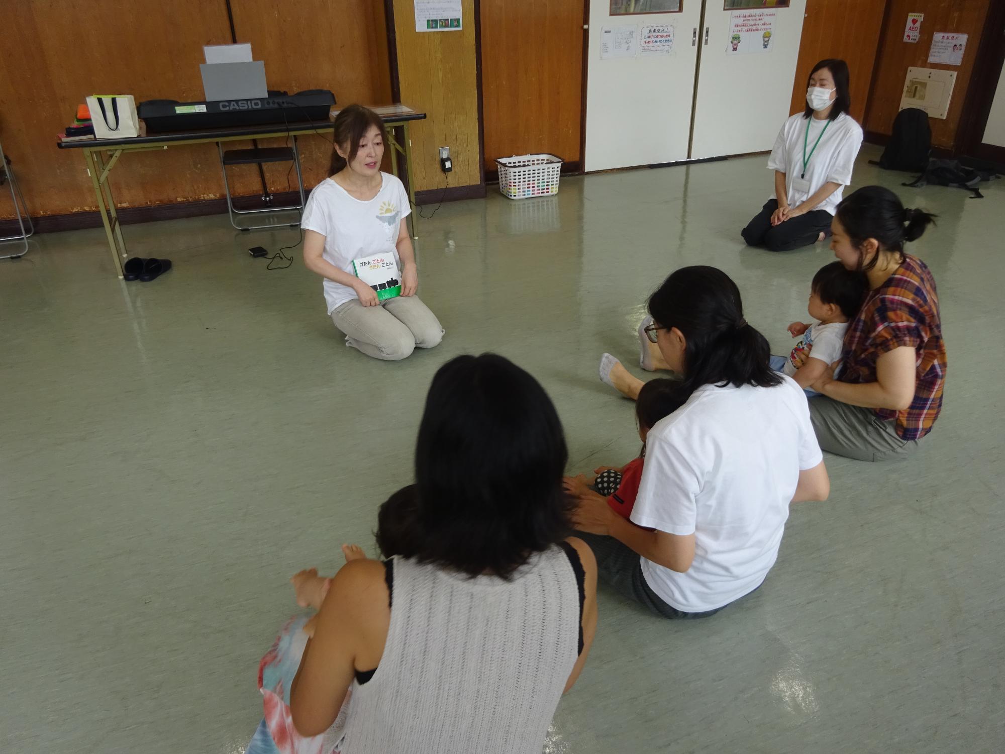 絵本の読み聞かせを聞いている幼児親子の写真