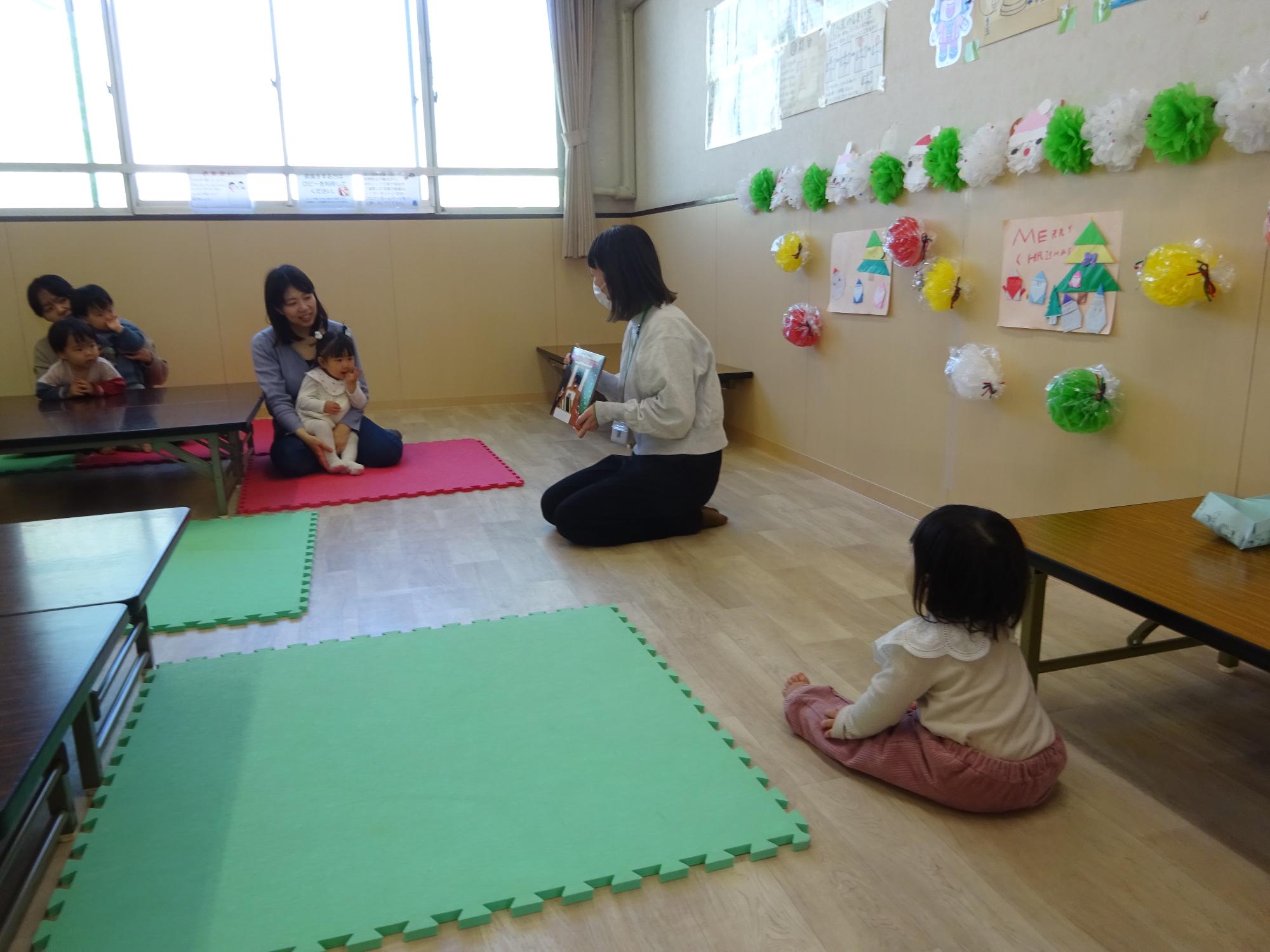 職員がクリスマスにちなんだ絵本のよみきかせをしている写真