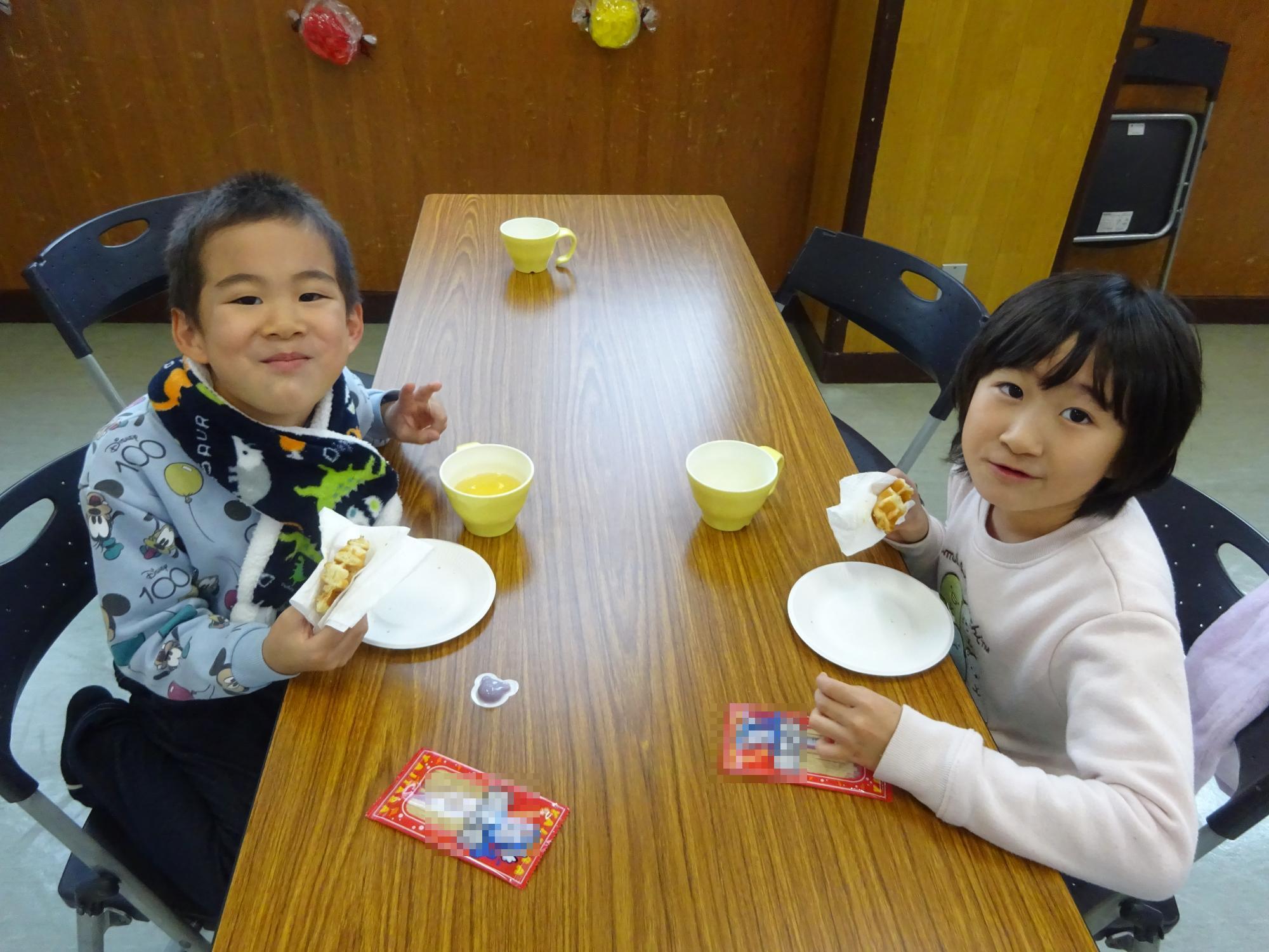 おやつタイムのワッフルを食べている子どもたちの写真