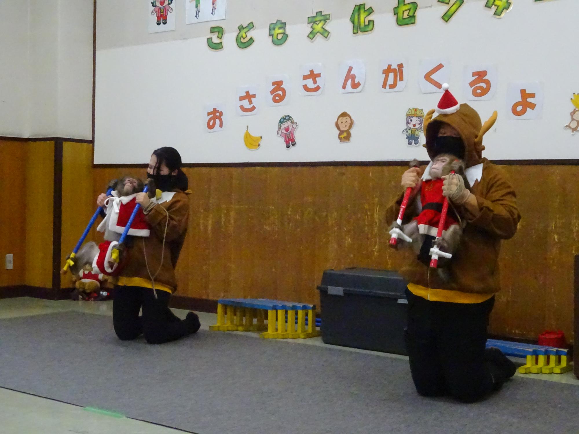 猿回しの芸を見ている大勢の子供や大人たちを後ろから撮影している写真