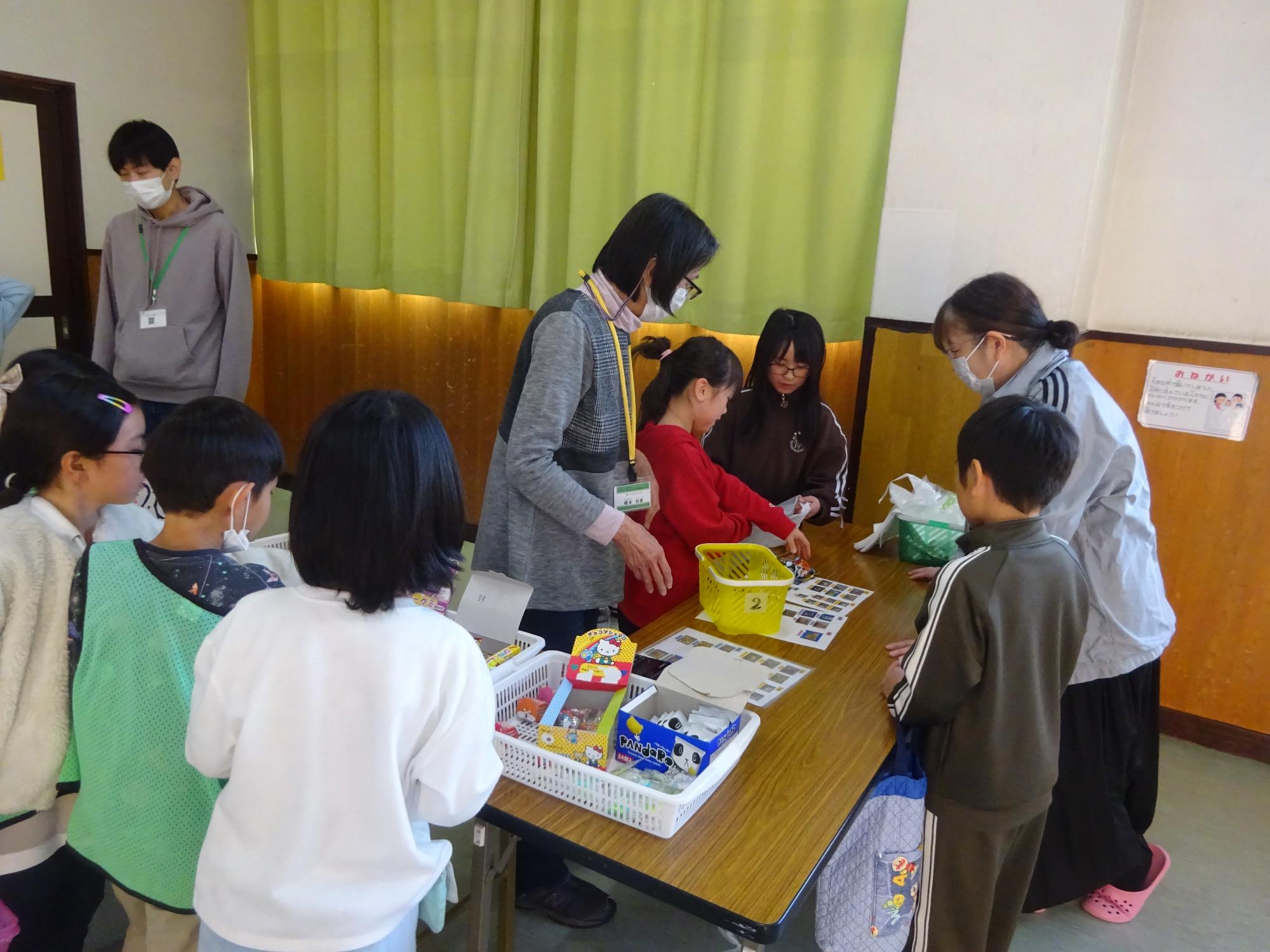 駄菓子を購入する子どもと、おみせやさんをする子どもの写真