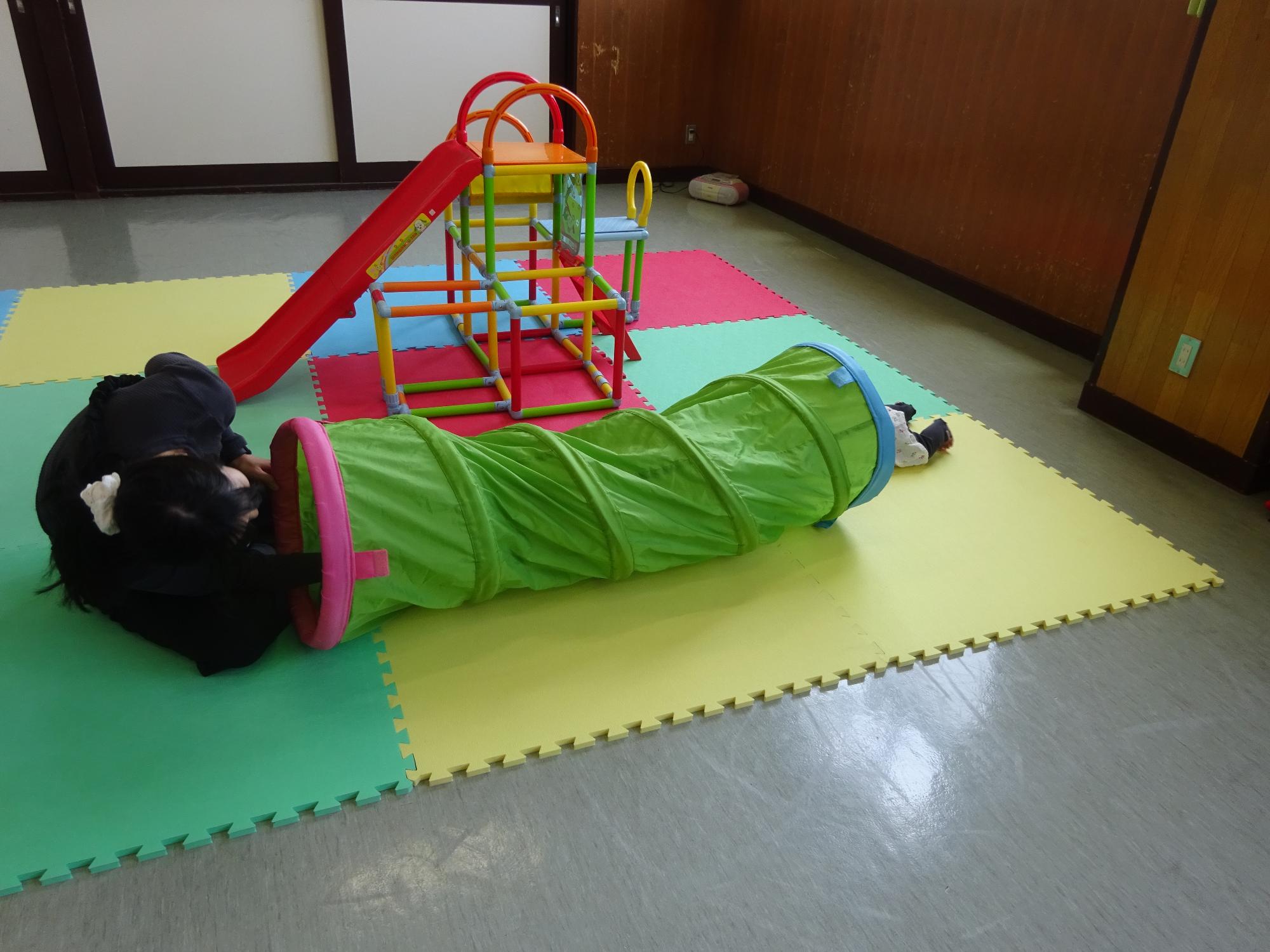 トンネルで遊ぶ幼児親子の写真