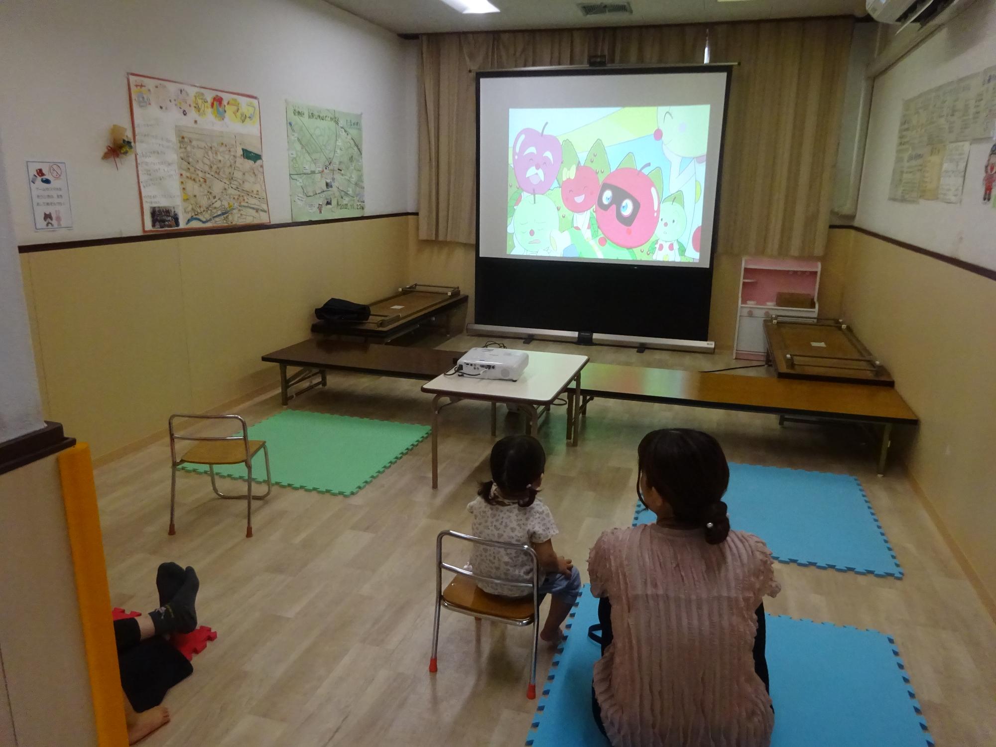 映画を観る幼児親子の写真