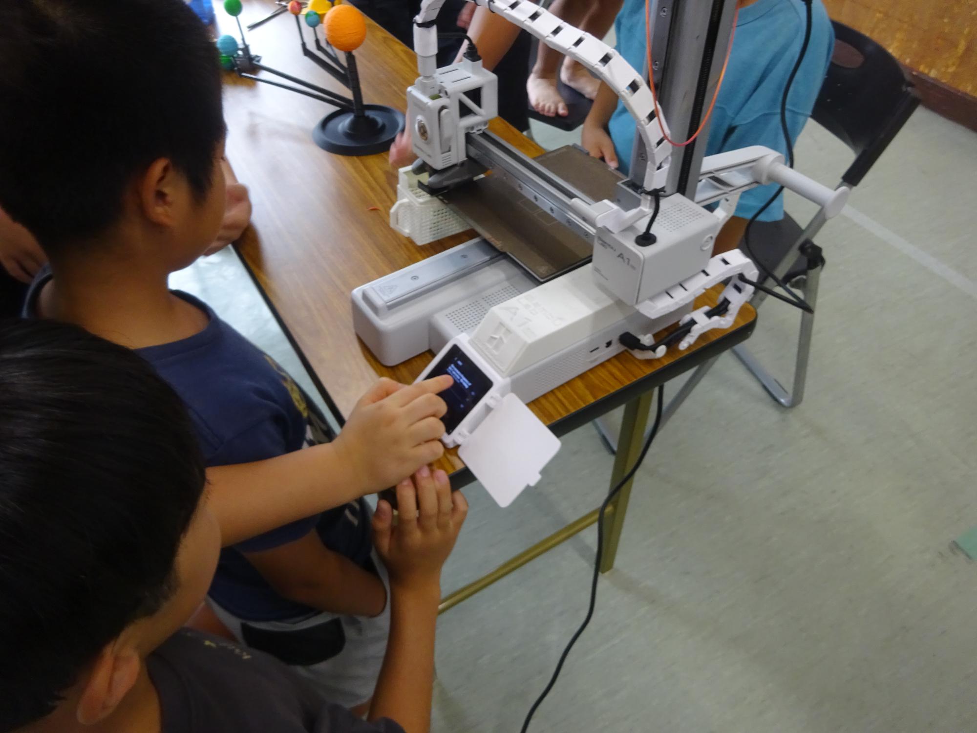 3Dプリンターの操作体験をしている子どもたちの写真