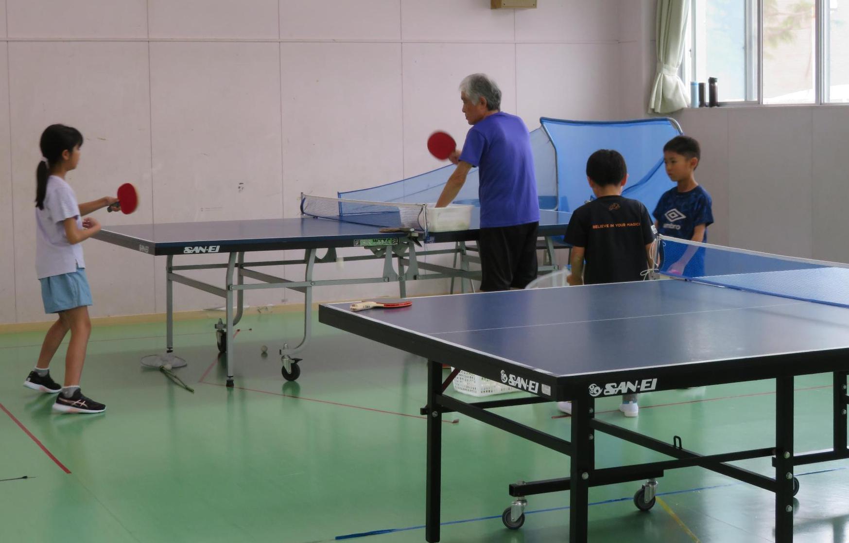 卓球クラブに所属する小学生児童が講師の指導のもと練習をしている様子の写真