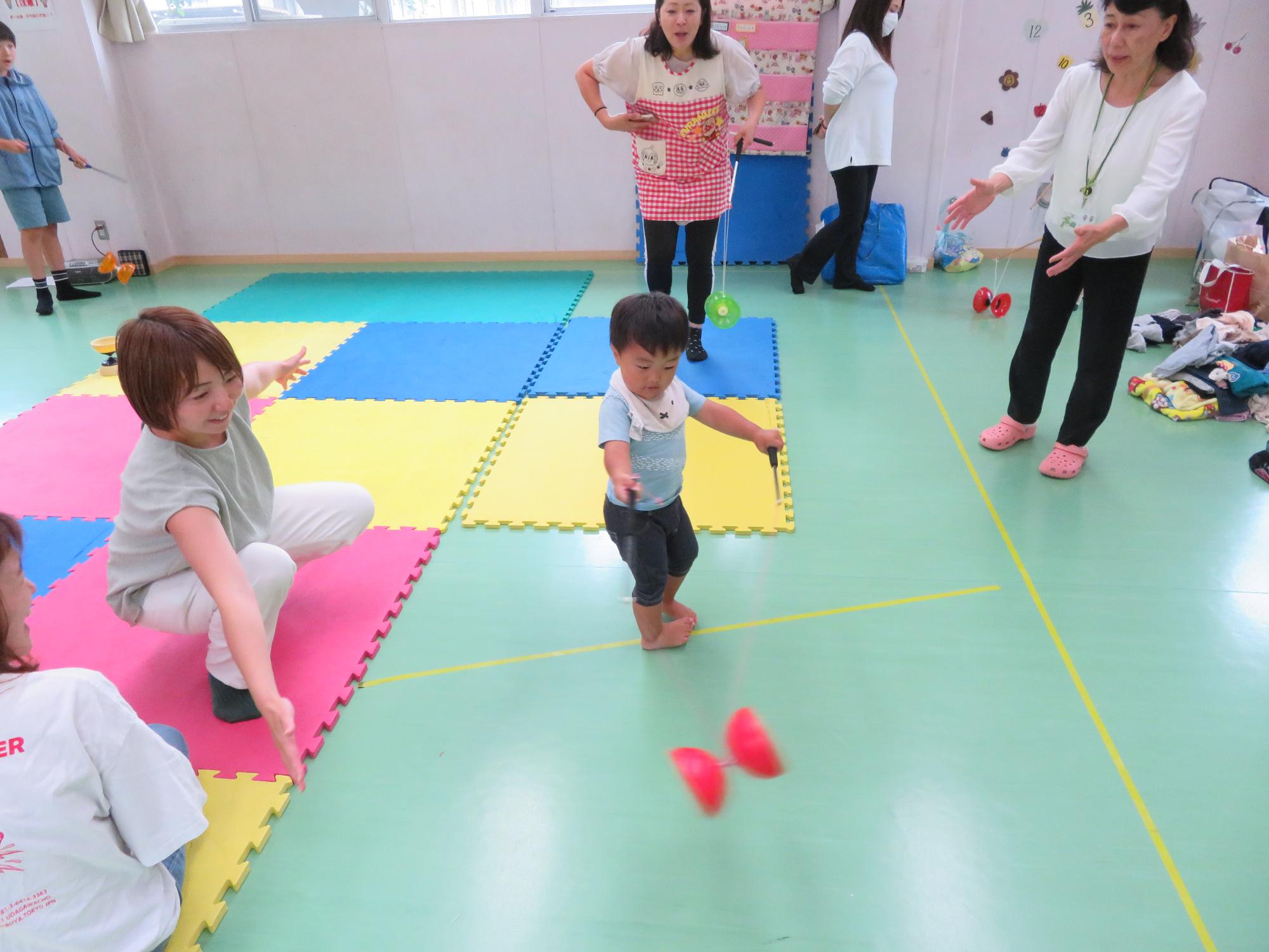 なかっこワークショップで中国ゴマをまわしながら自分も回っている幼児さんの写真