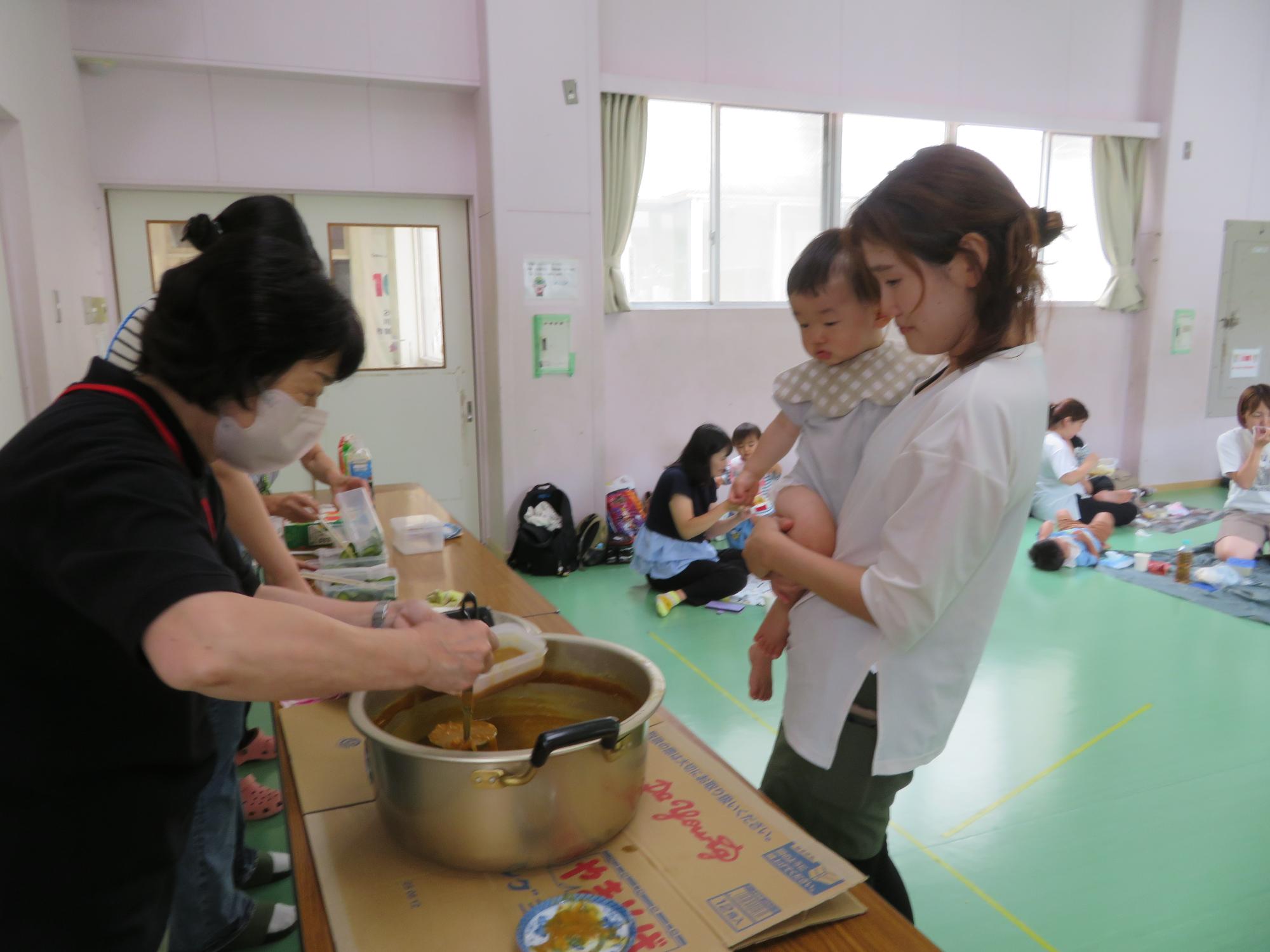 職員からカレーを受け取る乳幼児親子の様子の写真
