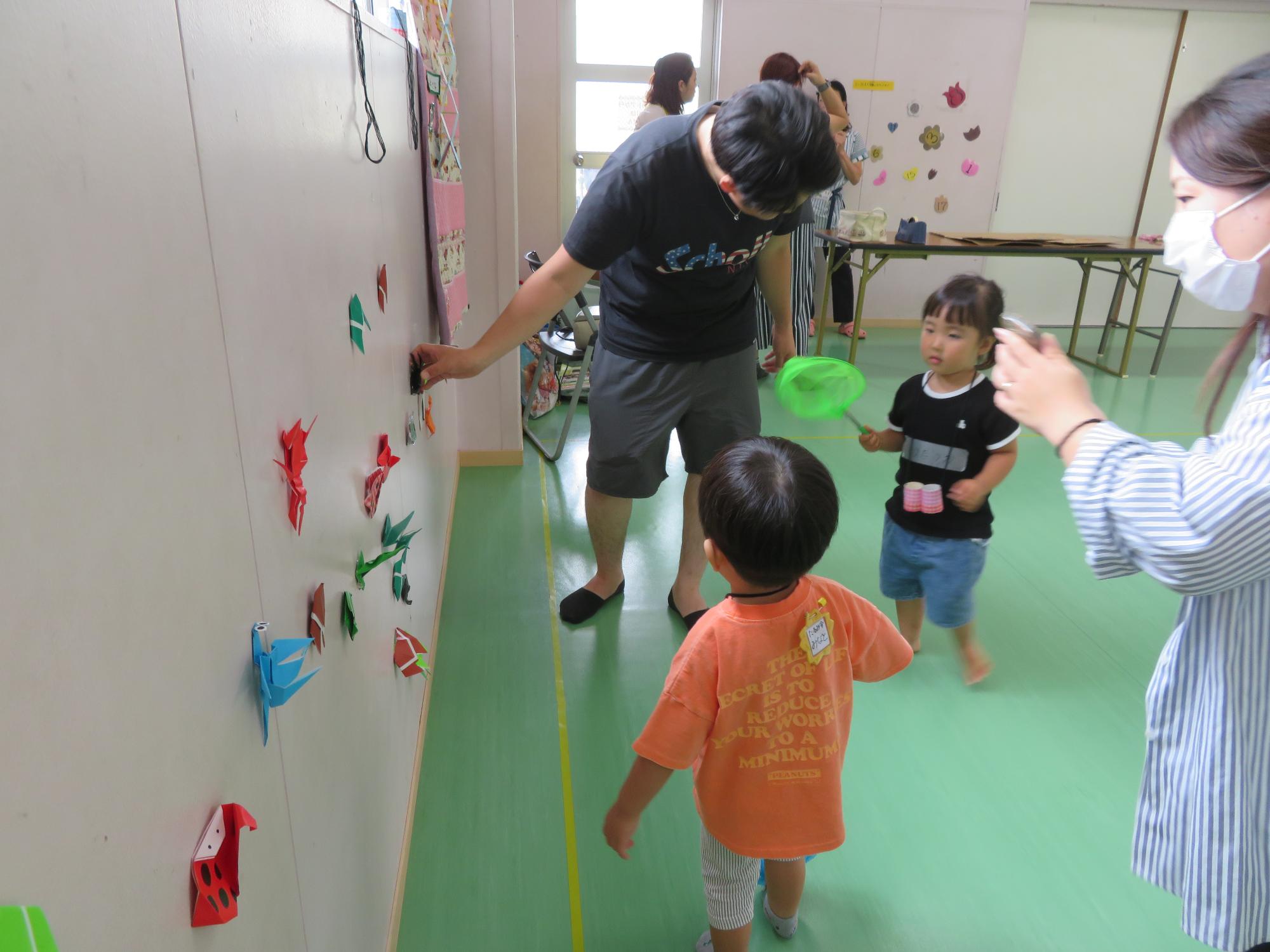 折り紙の虫を捕まえて遊ぶ幼児さんの様子の写真