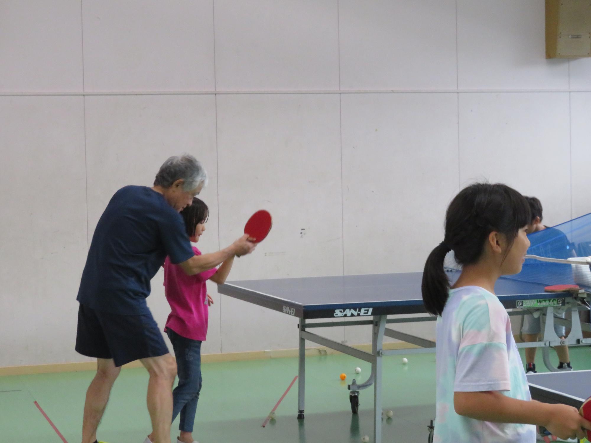講師にラケットの持ち方や打ち方を習う小学生の写真