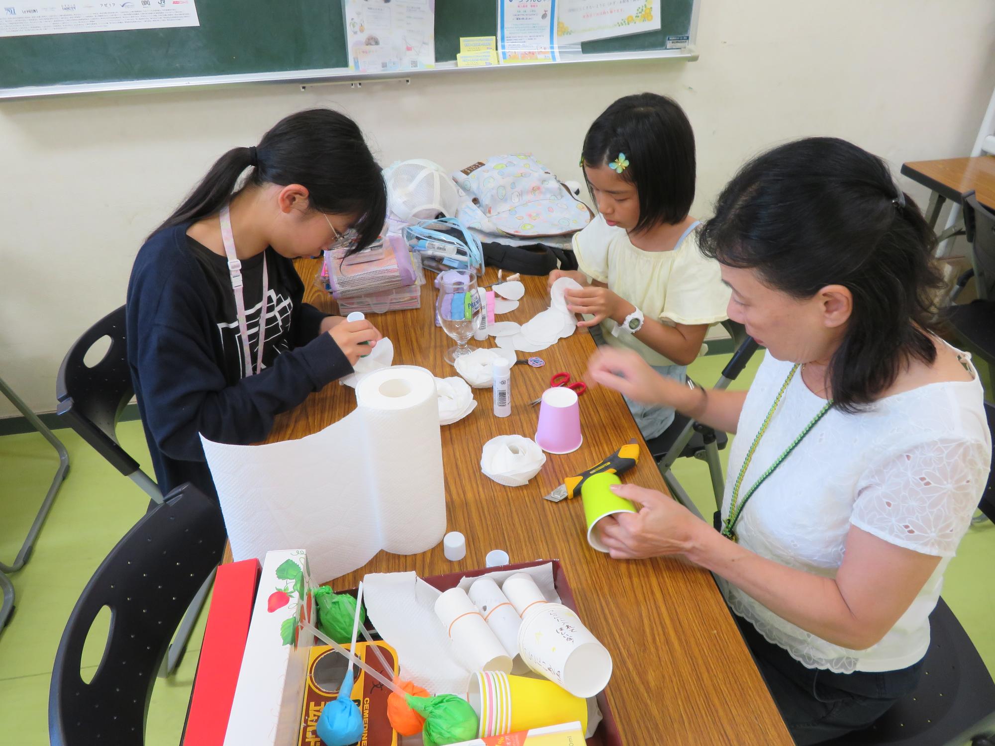 学習室で工作を楽しむ館長と小学生児童の様子の写真