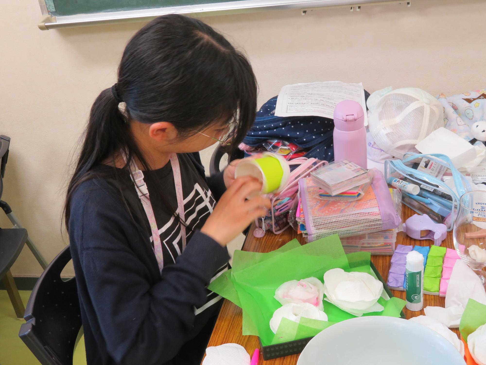紙コップにキッチンペーパーを貼り付けてバラの花びらを作る小学生の様子の写真