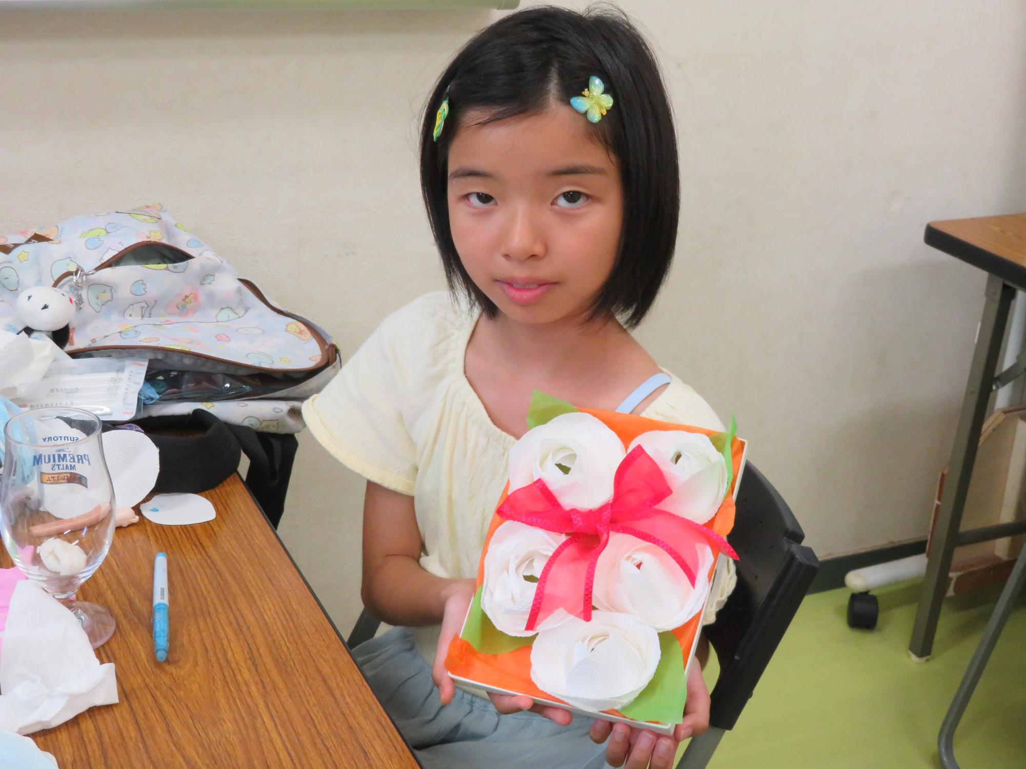 キッチンペーパーで作ったバラを箱に詰めてデコレーションした作品と小学生の写真