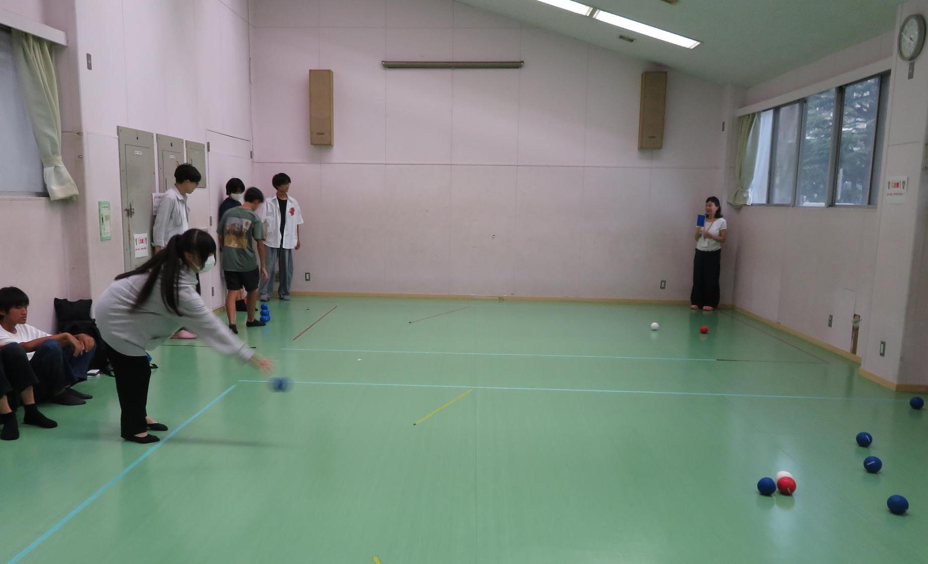 狙いを定めて青いボッチャの玉を投げる中学生の写真