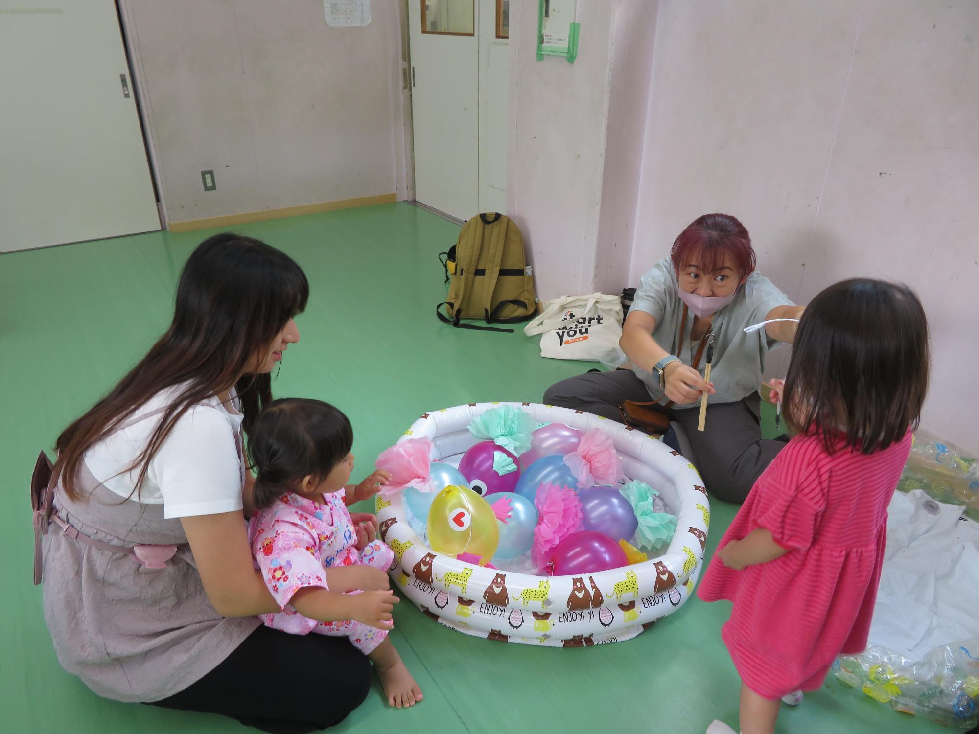 お魚釣りで遊ぶ幼児親子の様子の写真