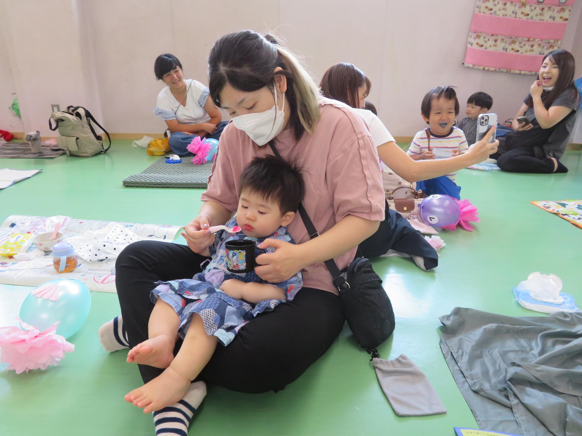 母親と一緒にかき氷を食べる幼児の様子の写真