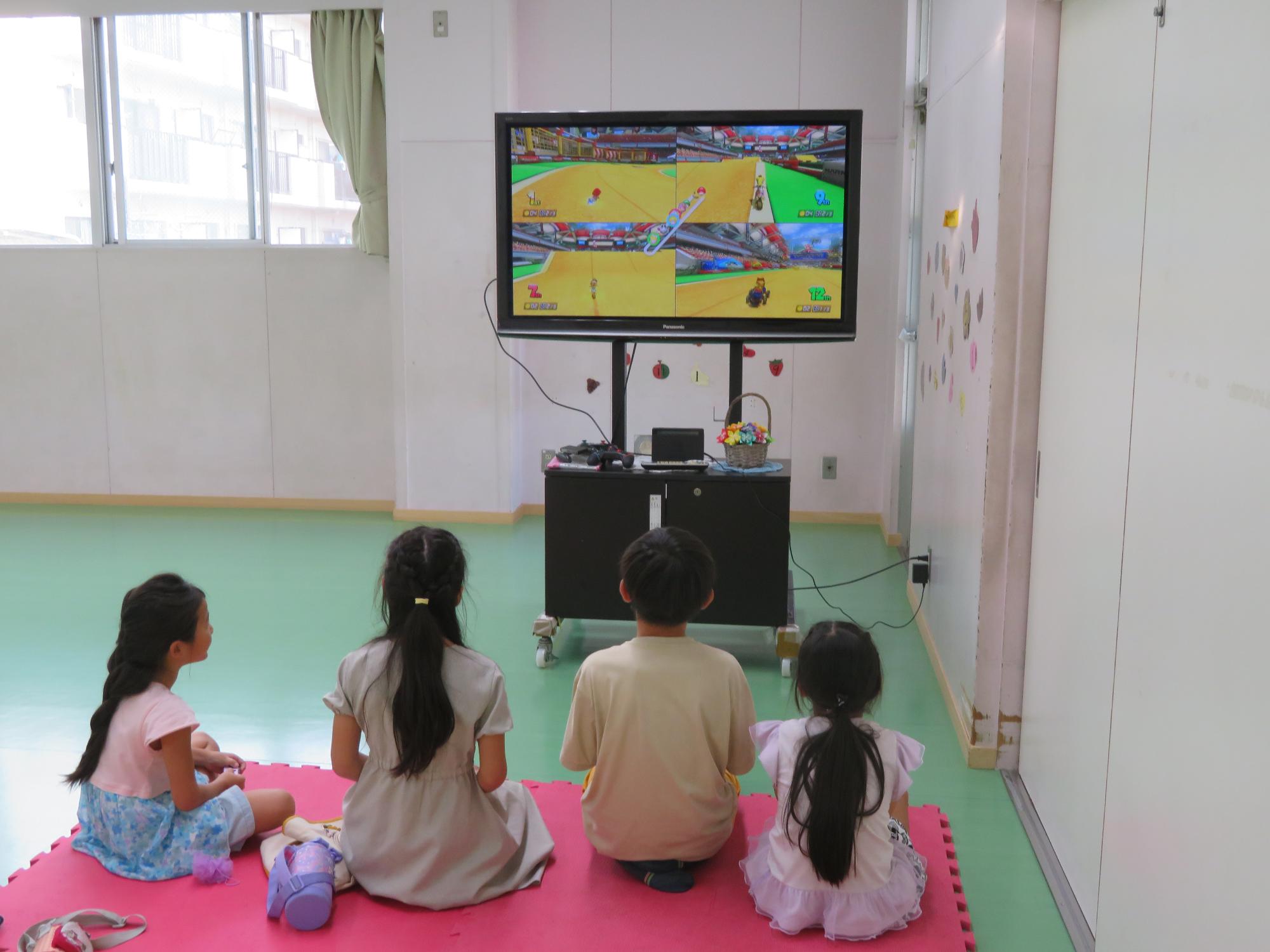 トレーニング室でテレビゲームで遊ぶ小学生児童の写真