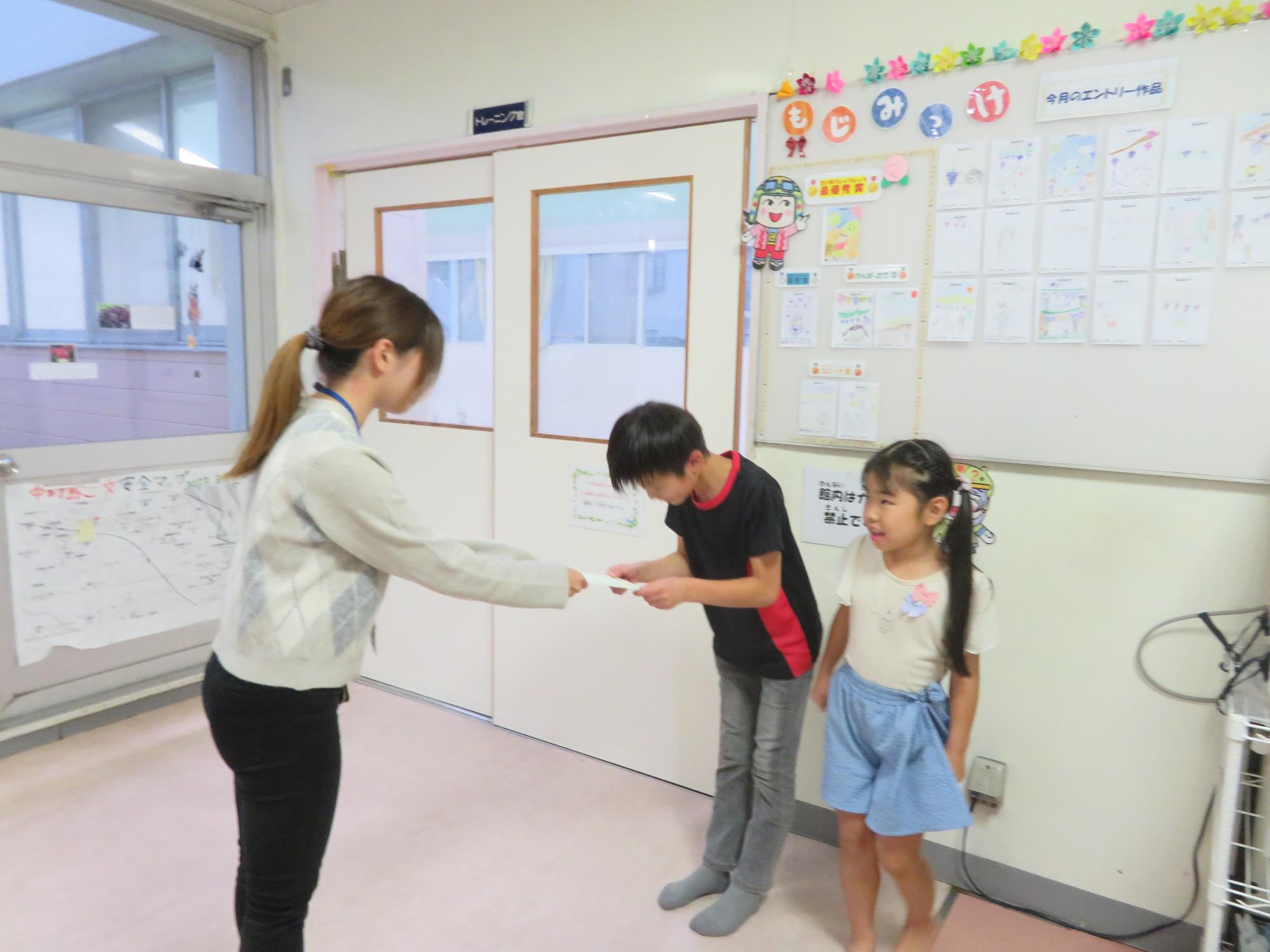 9月の「もじみっけ」で最優秀賞を獲ったイラストを描いた児童が表彰される様子