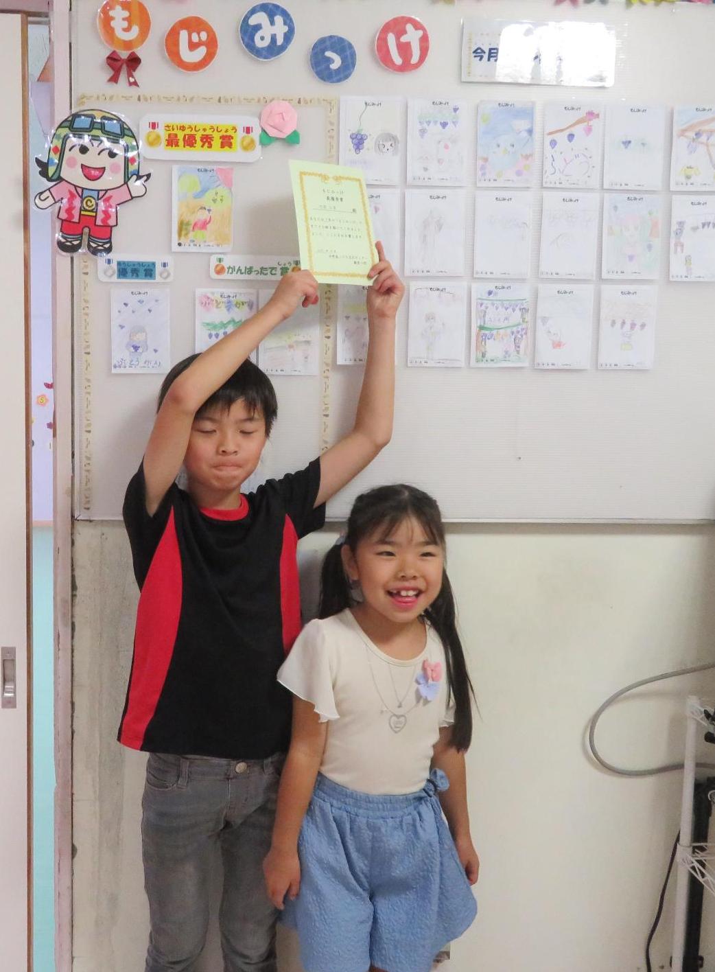 9月の「もじみっけ」で最優秀賞を獲った児童とそのイラストの写真
