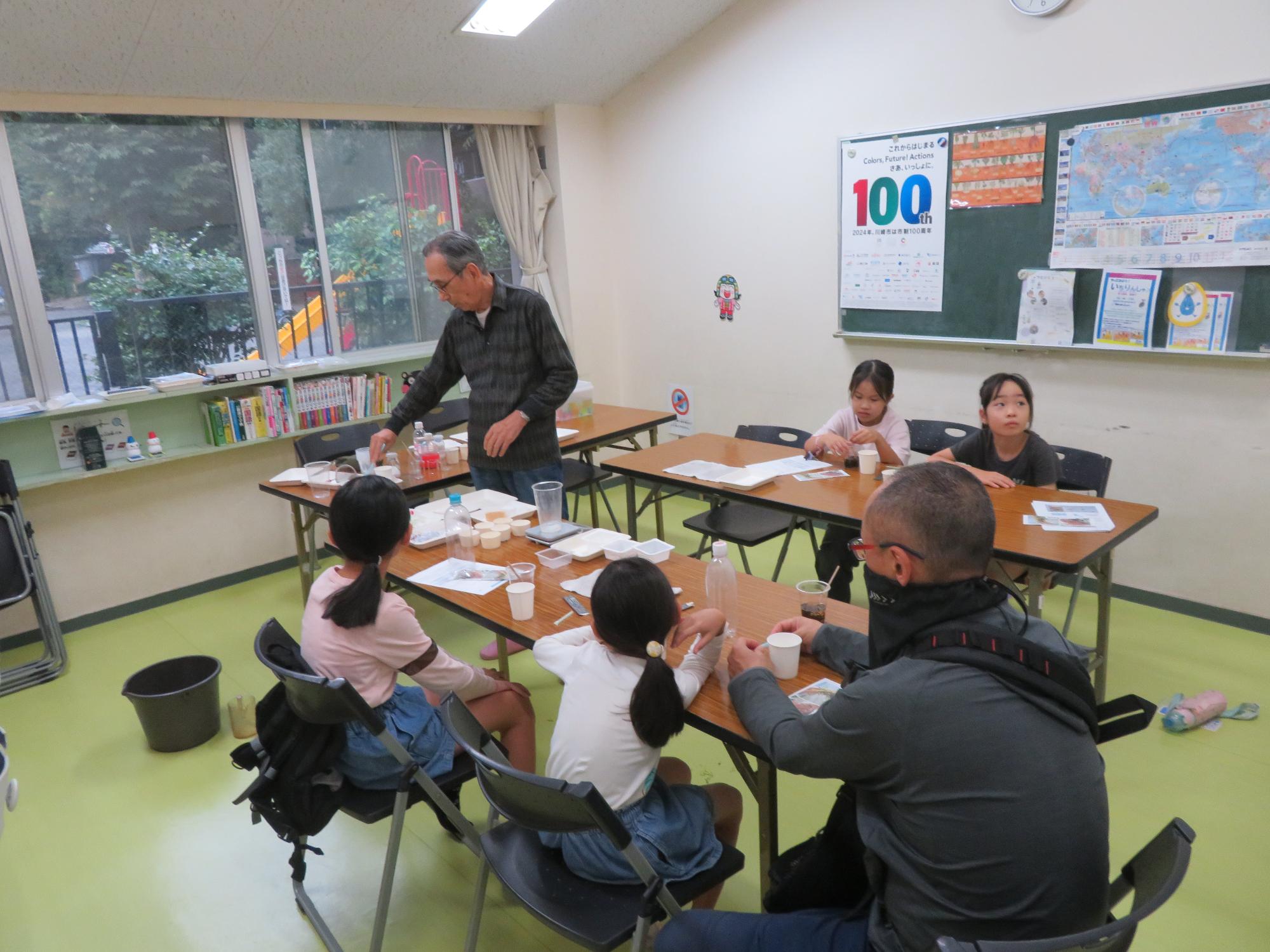 おもしろサイエンスに集まった参加者が講師に説明を聞いている様子の写真