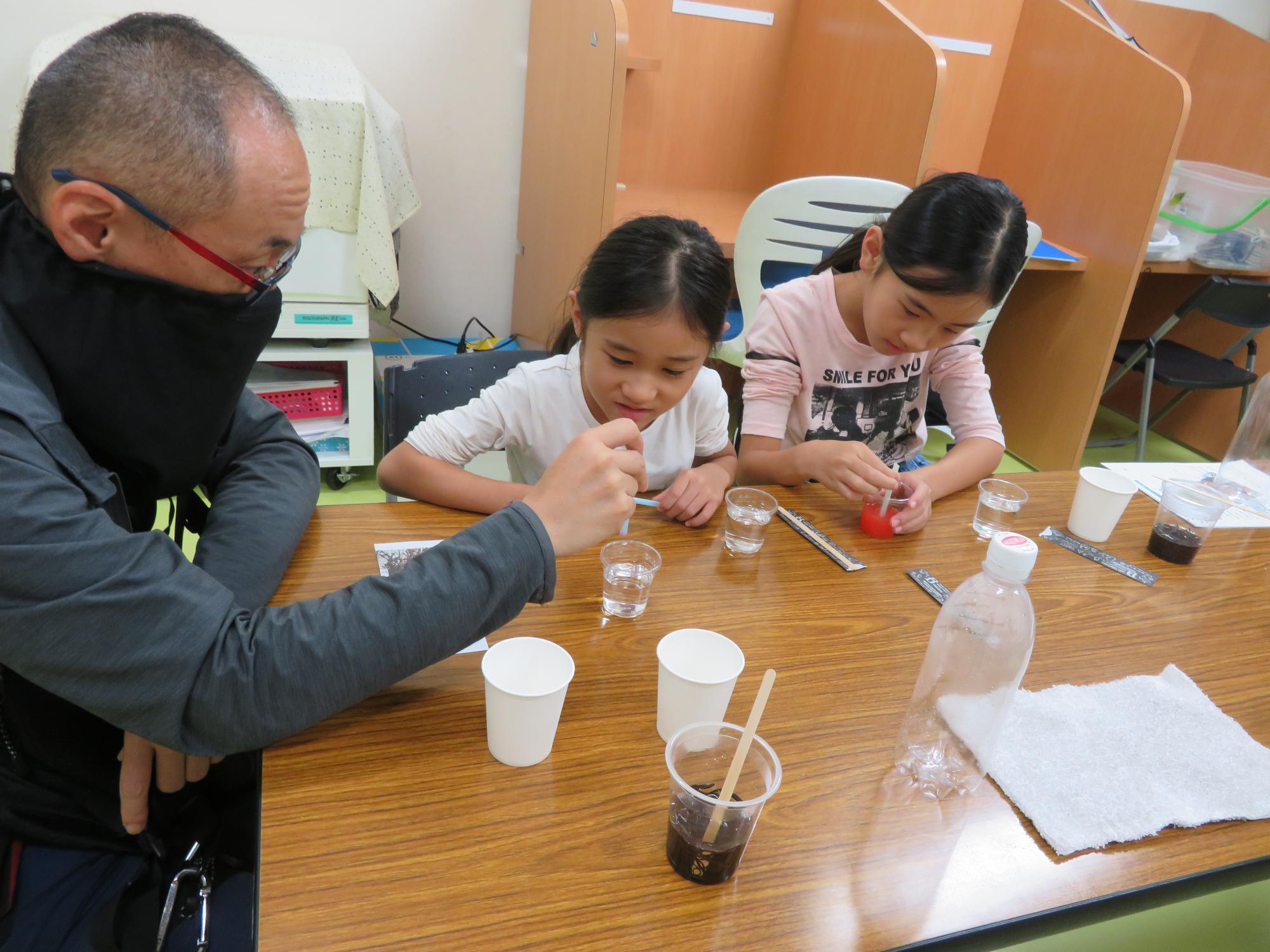 講師の指導を聞きながら実験をする参加児童の様子の写真