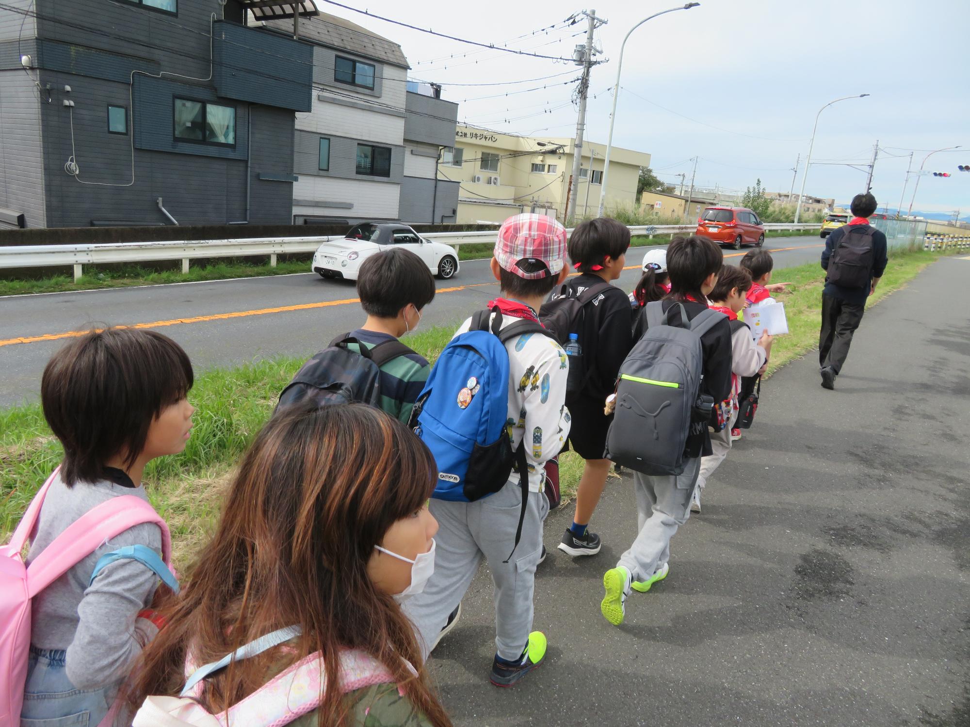 中野島こども文化センターから参加した児童たちが多摩川沿いを歩いている様子の写真