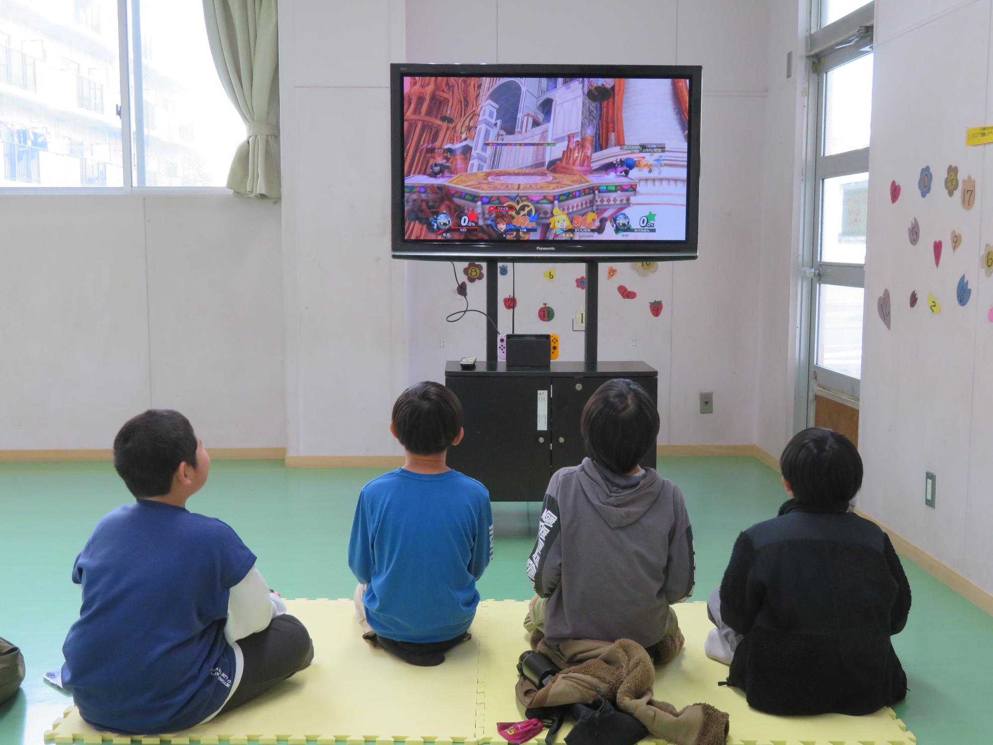 トレーニング室でテレビゲームで遊ぶ小学生児童の様子の写真