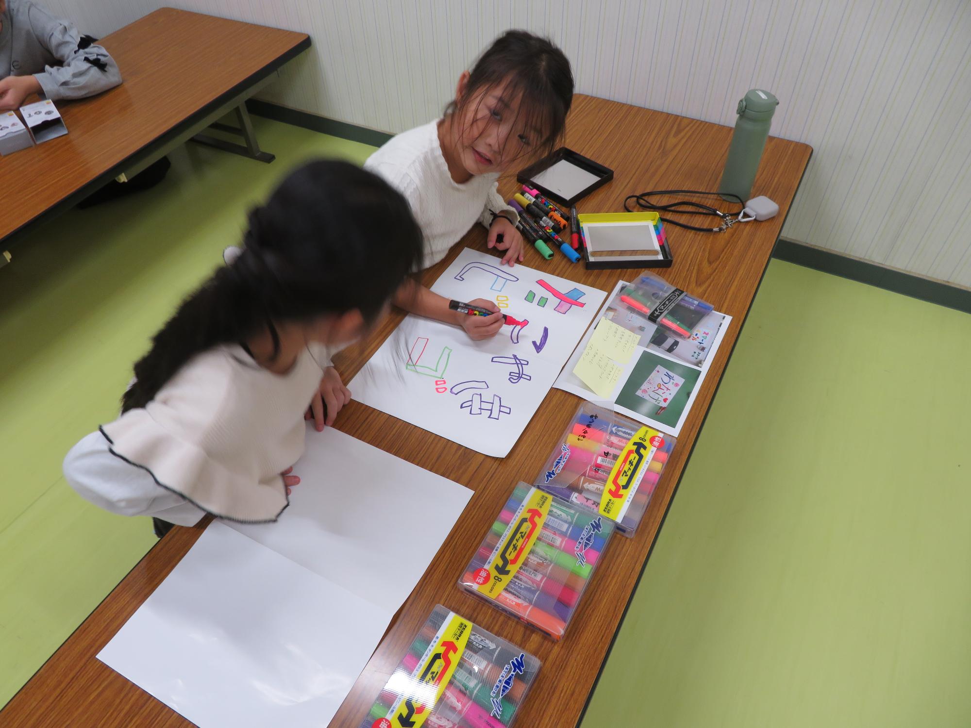 こ文のお祭りに向けてゲームブースの看板を作っている小学生児童の写真