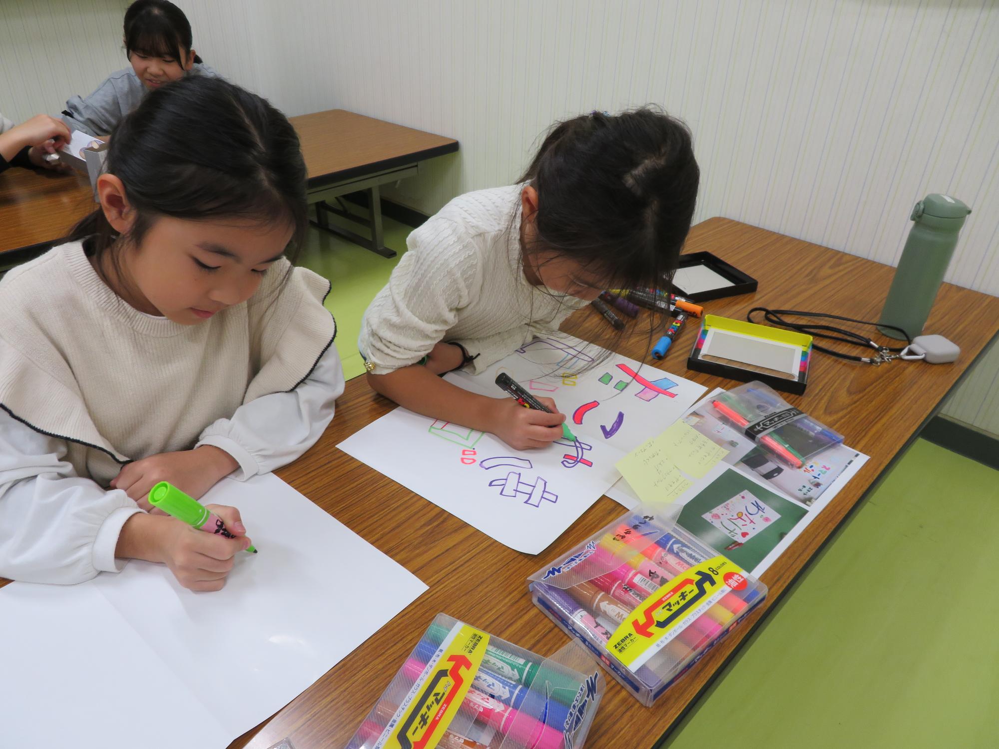 こ文のお祭りに向けてゲームブースの看板を作っている小学生児童の写真