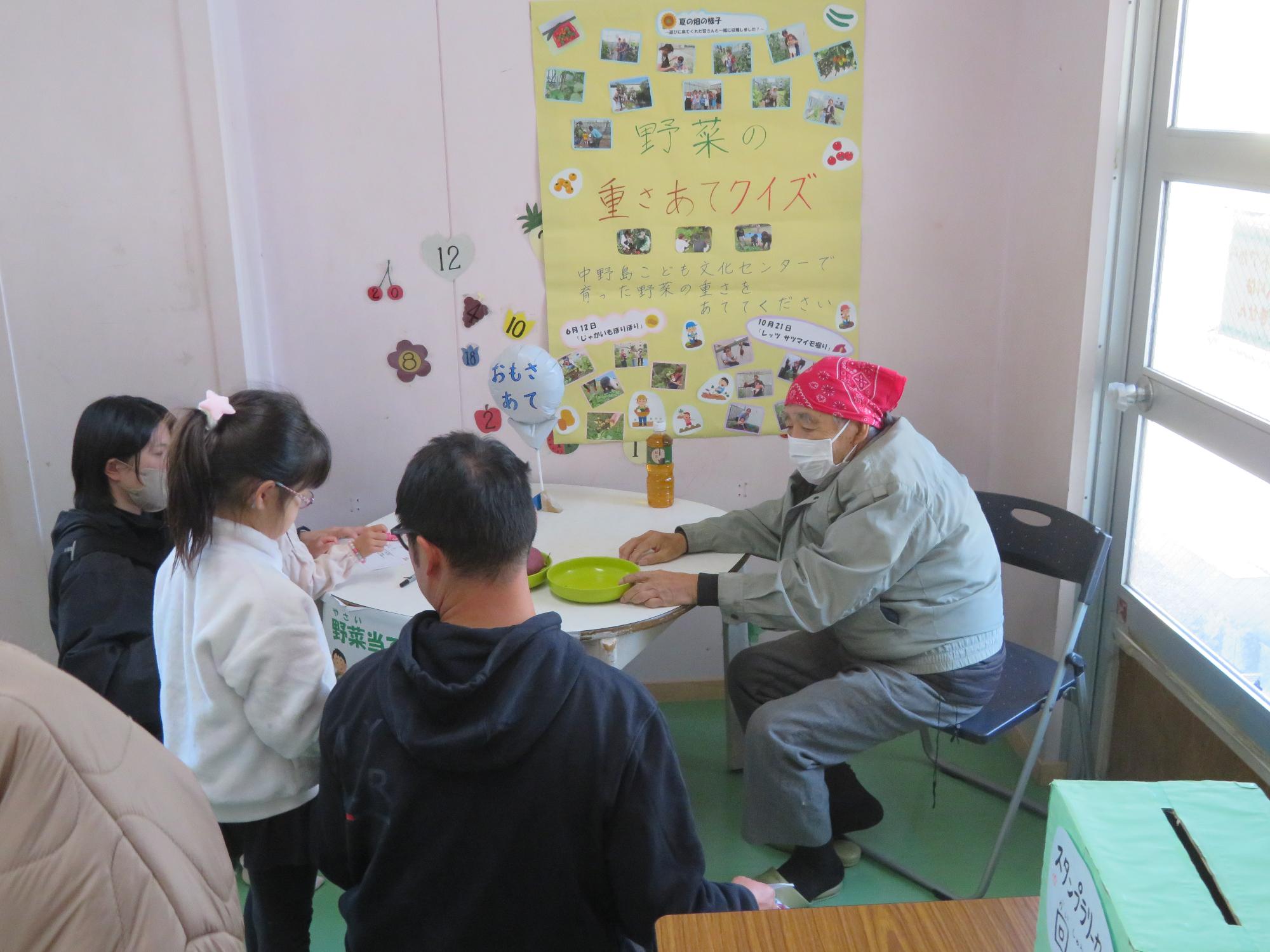 こども文化センターまつりのゲームコーナーの1つである野菜の重さ当てクイズの様子の写真