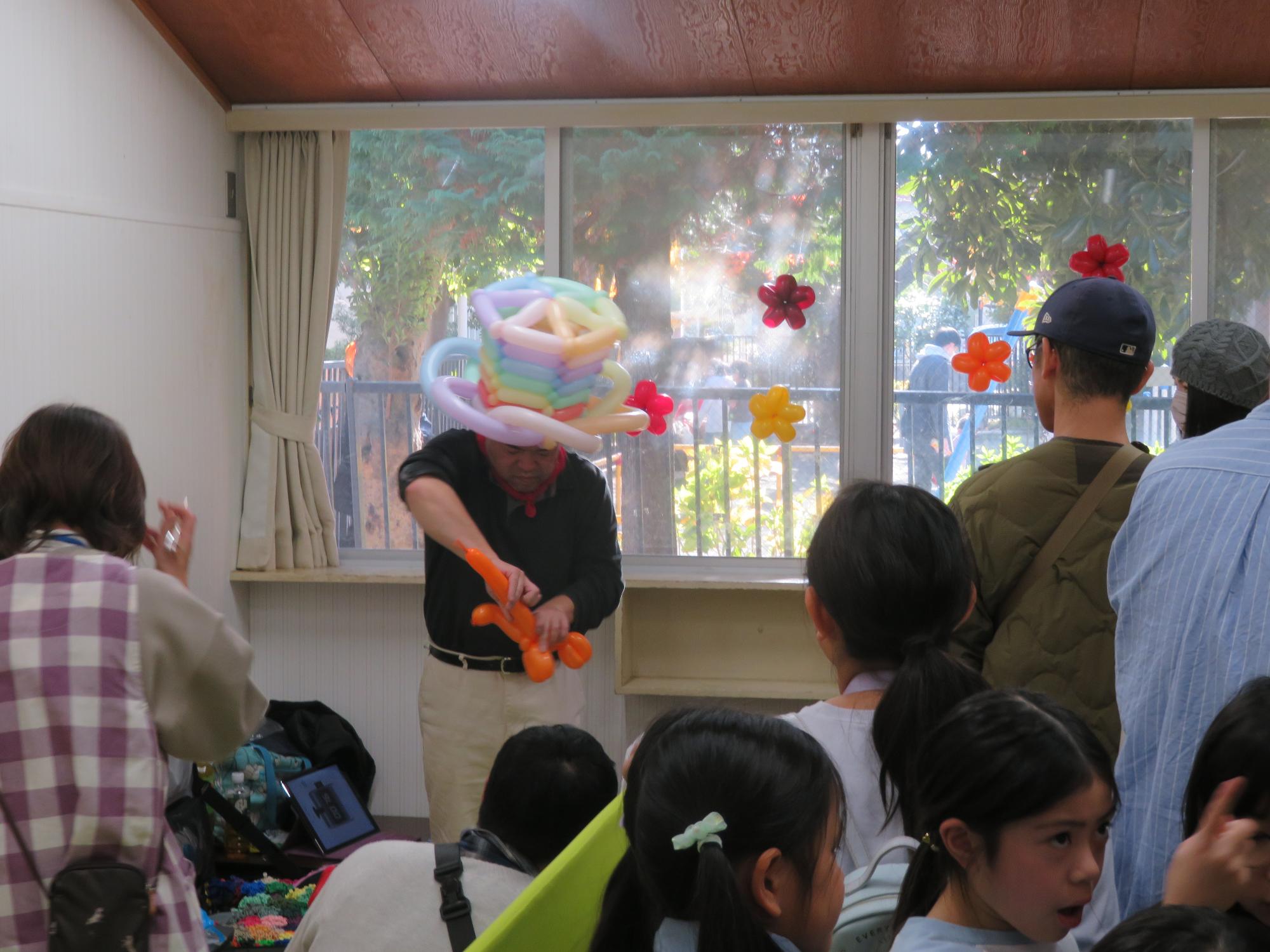 バルーンアートのコーナーで子どもたちに風船を配るボランティアの方の様子の写真
