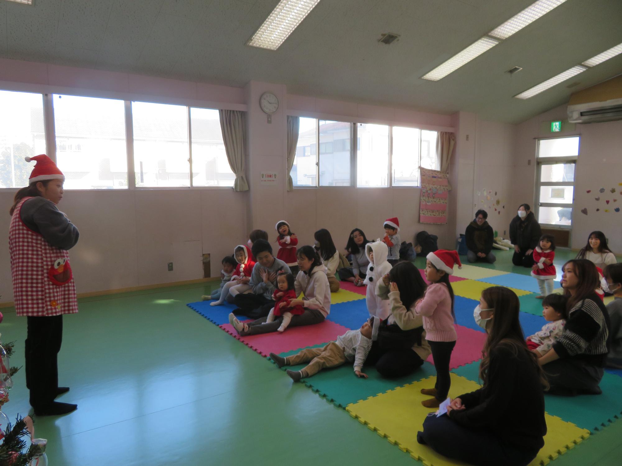 乳幼児行事の司会を担当してくださった先生と参加乳幼児親子の様子の写真