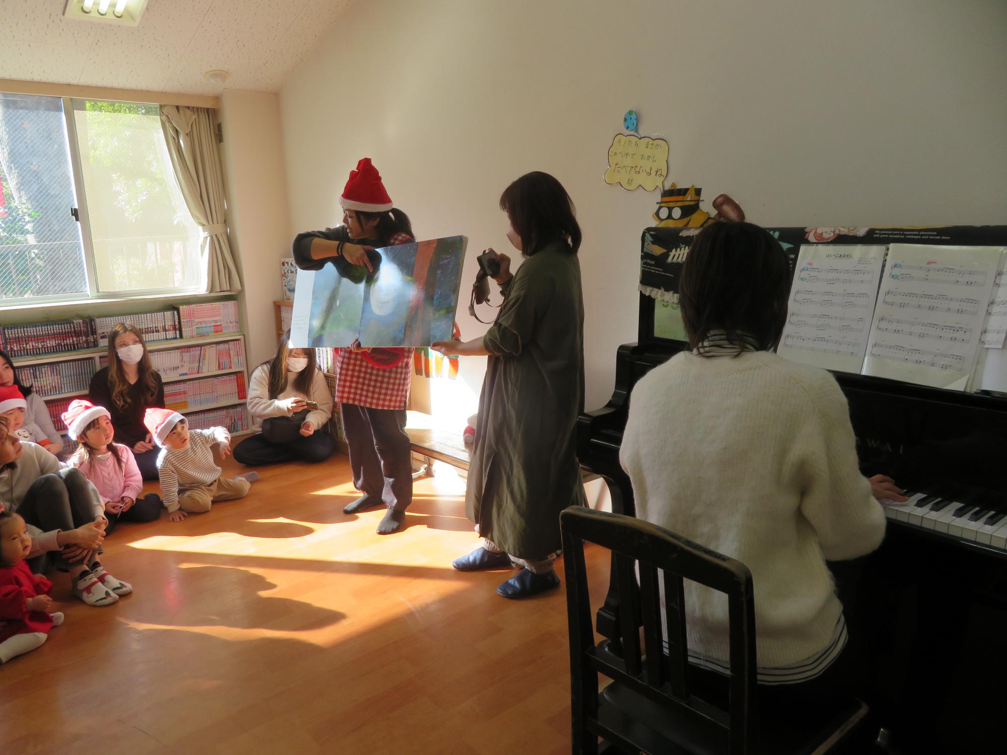 ピアノの演奏に合わせて絵本の読み聞かせをする先生の写真