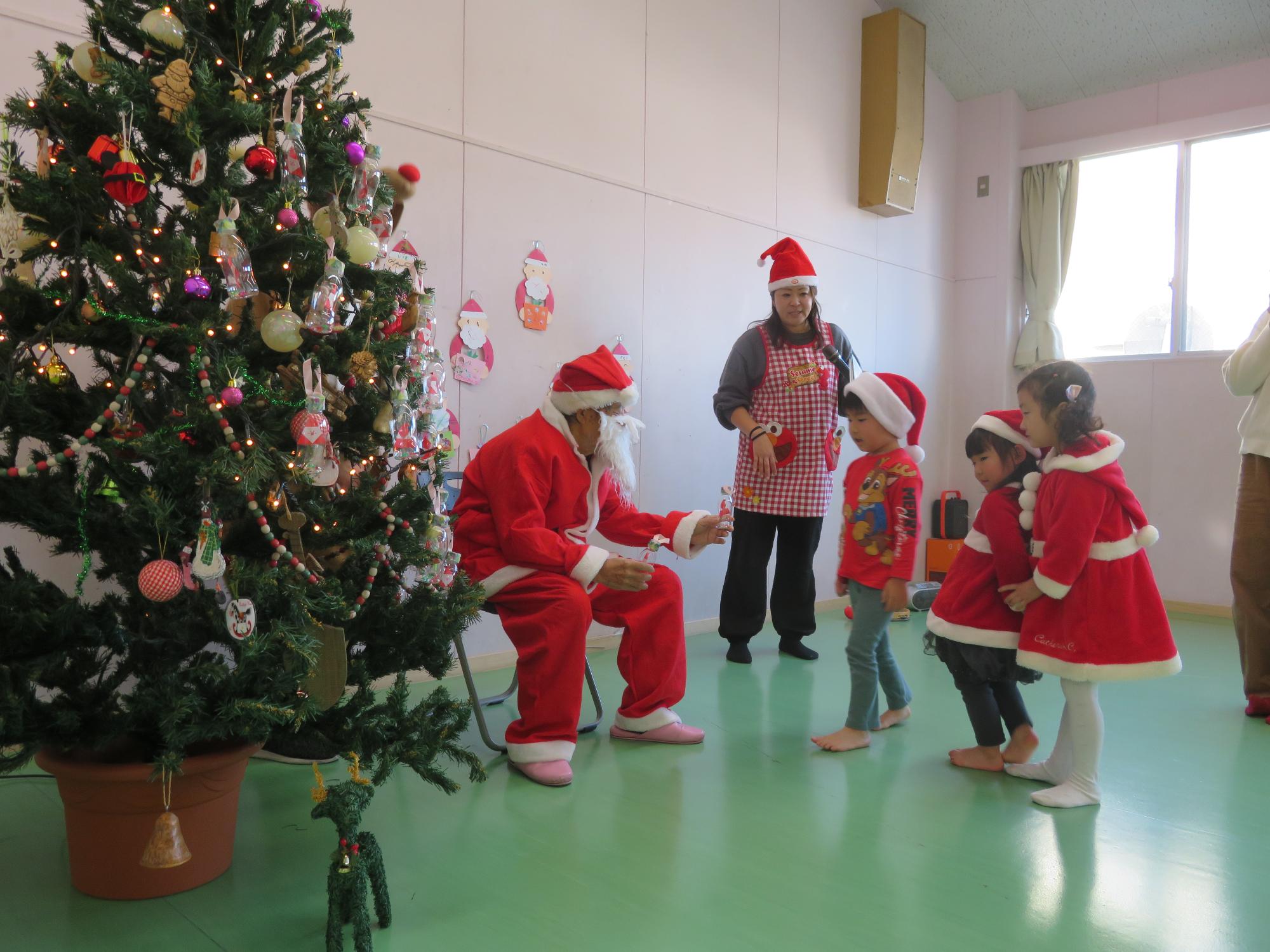 サンタに扮した地域ボランティアの方にプレゼントをもらう参加幼児の様子の写真